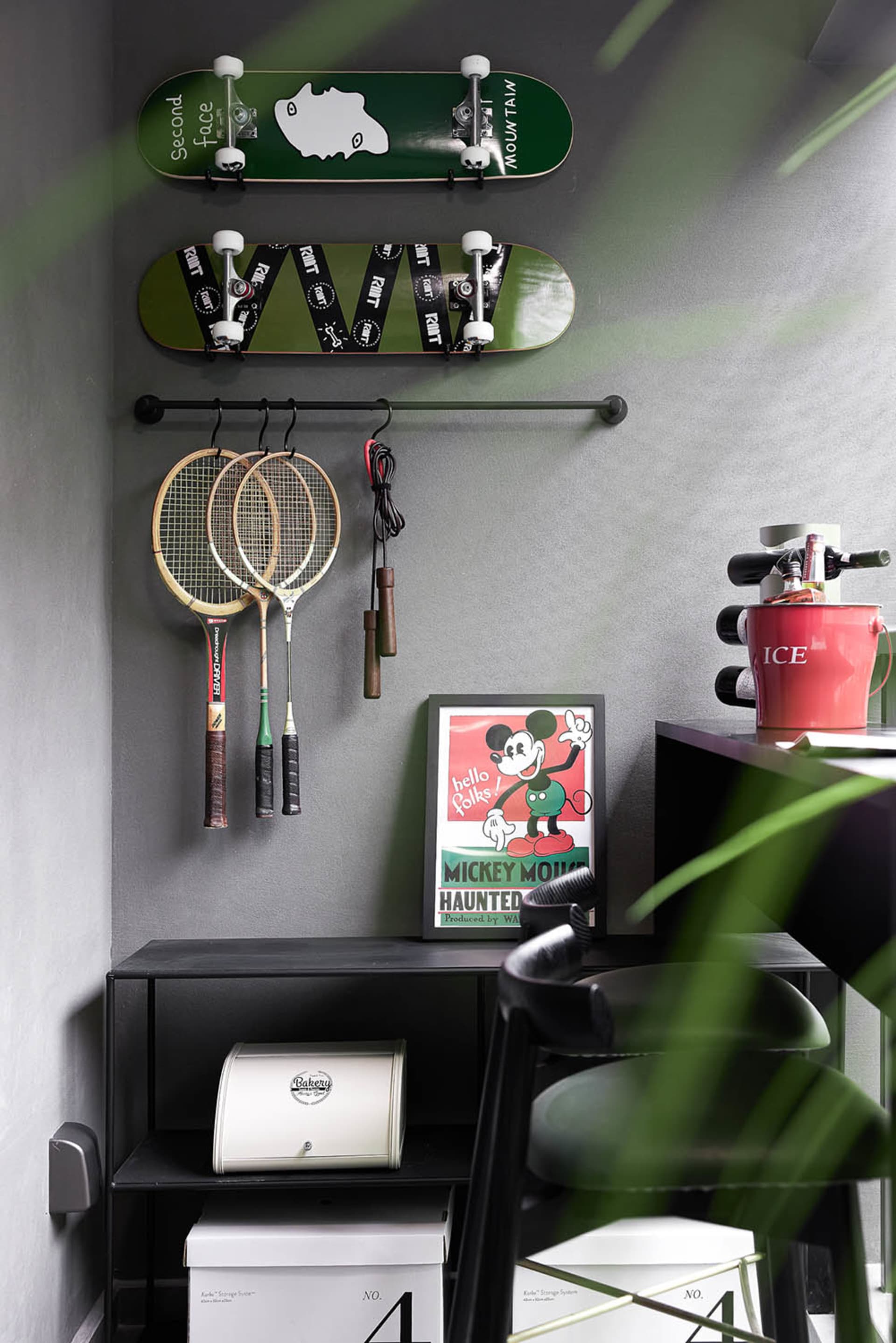 A home office with industrial design elements, including concrete walls, metal furniture, and skateboard decks hanging on the