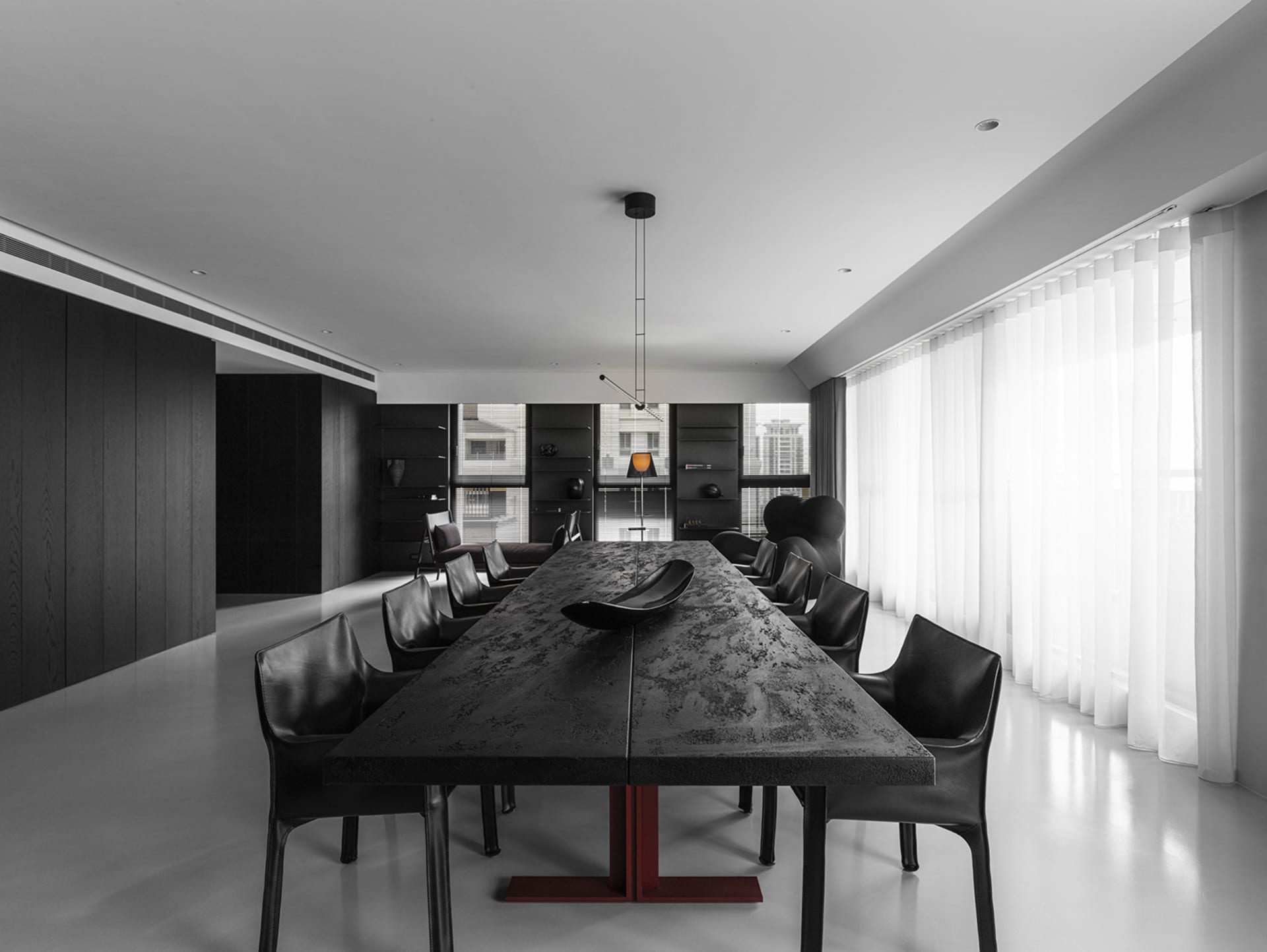 A modern black dining table with white curtains in a minimalist residential interior