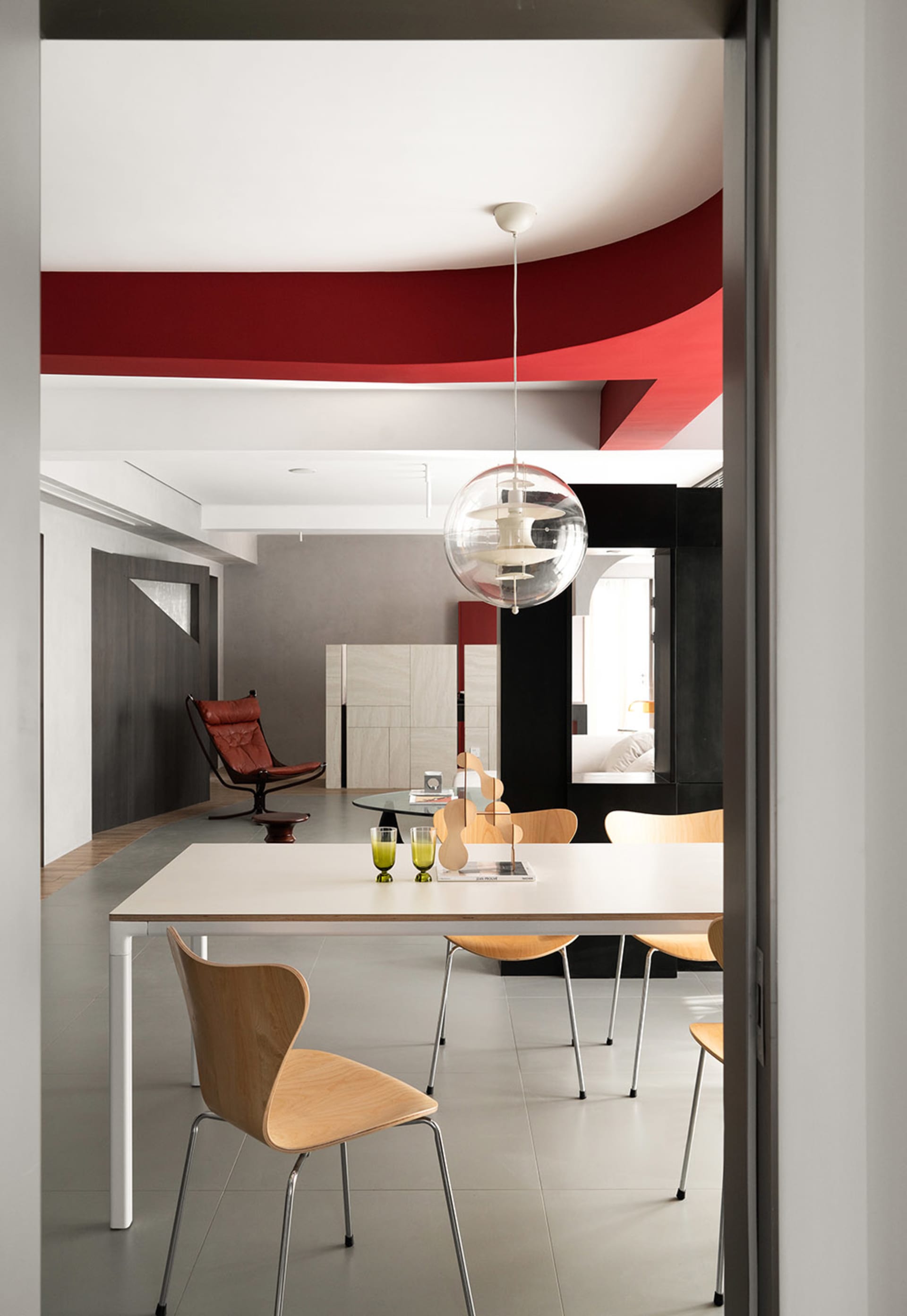 A modern dining room with a table, chairs, and a hanging light fixture.
