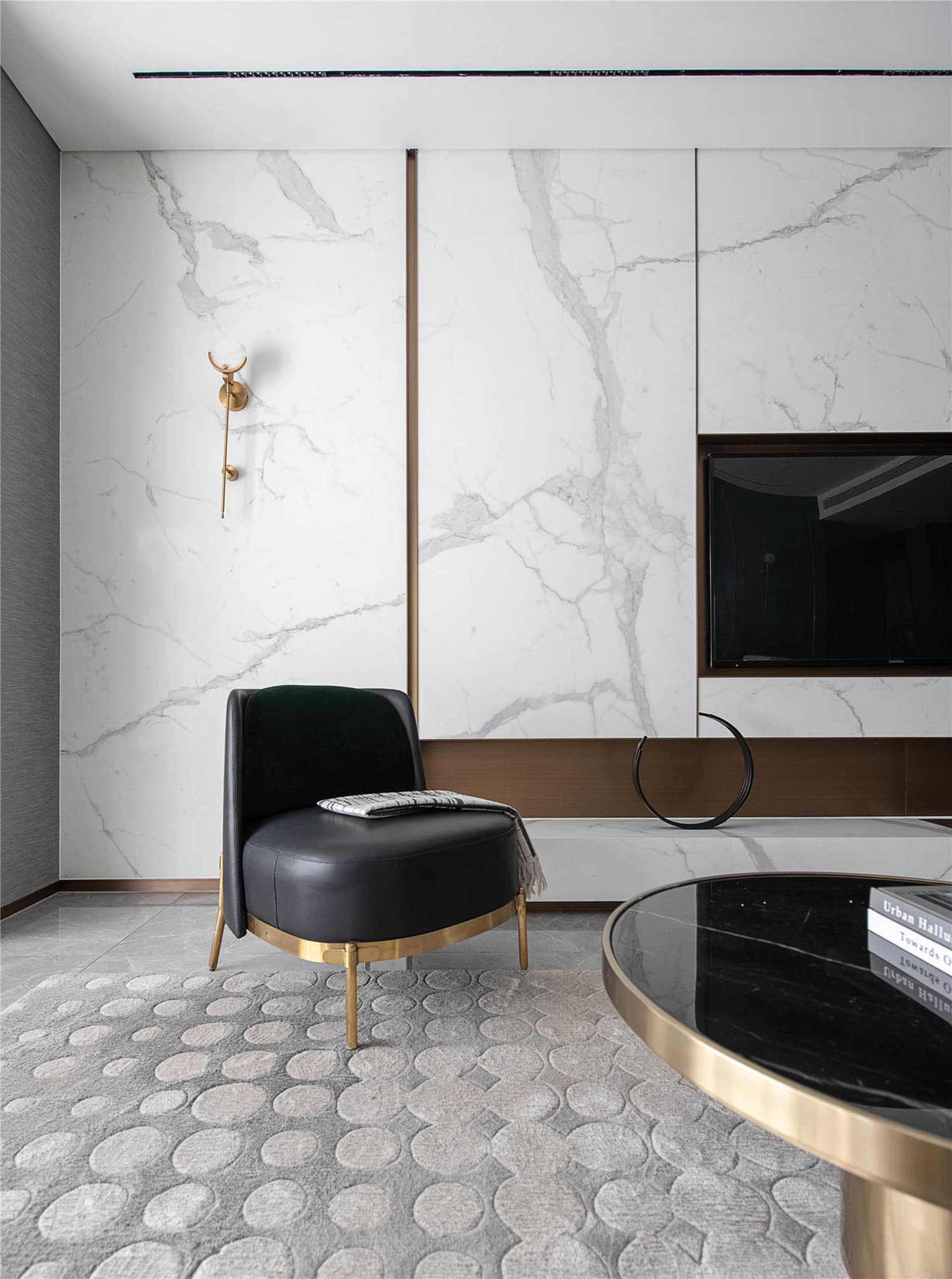 A modern living room with marble walls and a black armchair.