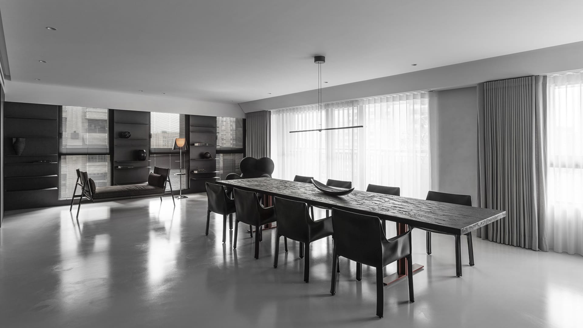 Modern minimalist dining room featuring a concrete table and black chairs.