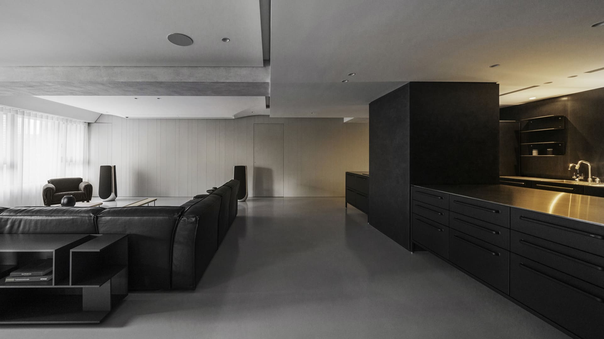 Modern minimalist interior featuring black and white design elements, concrete flooring, wood accents, and metal fixtures