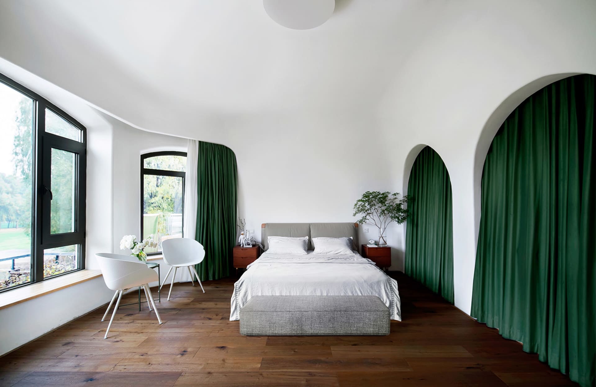 A modern bedroom with white furniture, green curtains, and a wood floor.