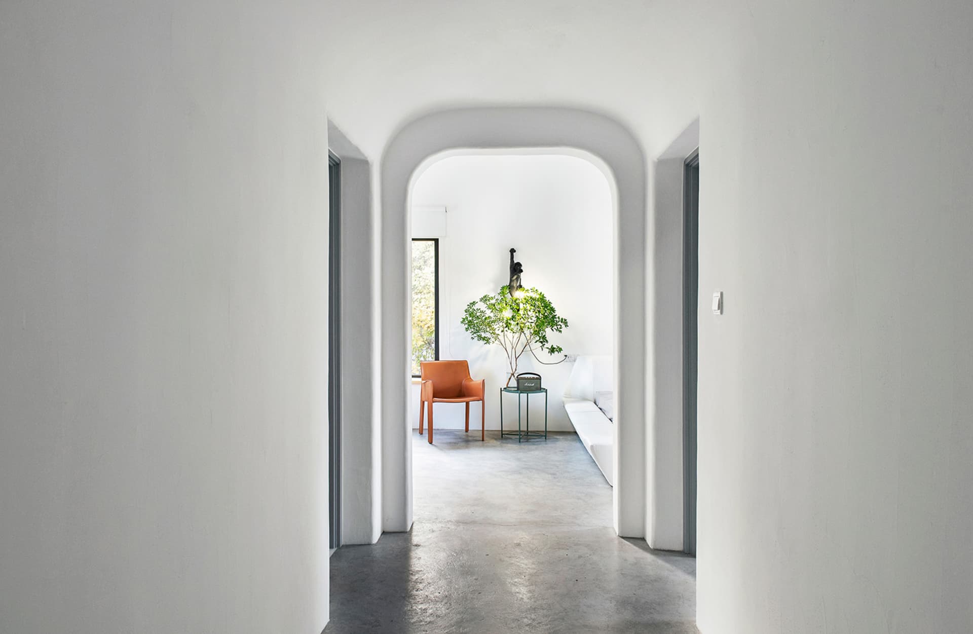 Modern minimalist interior with concrete flooring and a white couch.