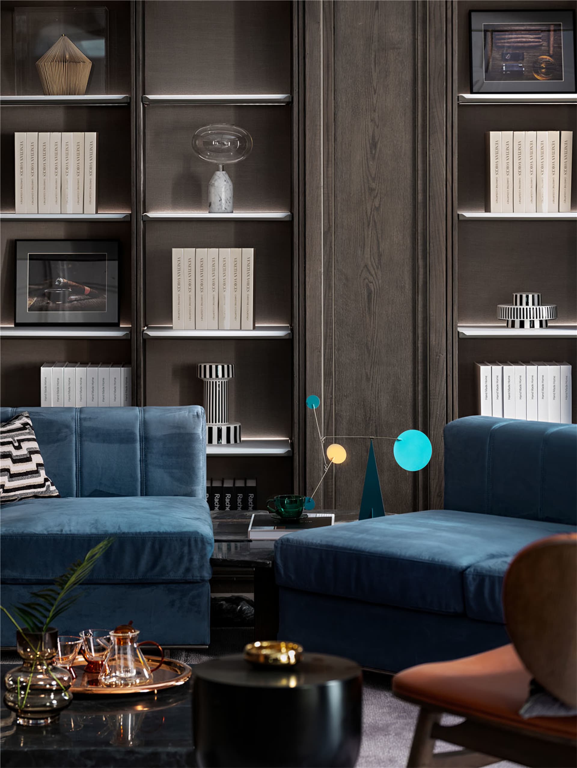 Modern living room with blue sofas, minimalist decor, and a mix of textures and materials.
