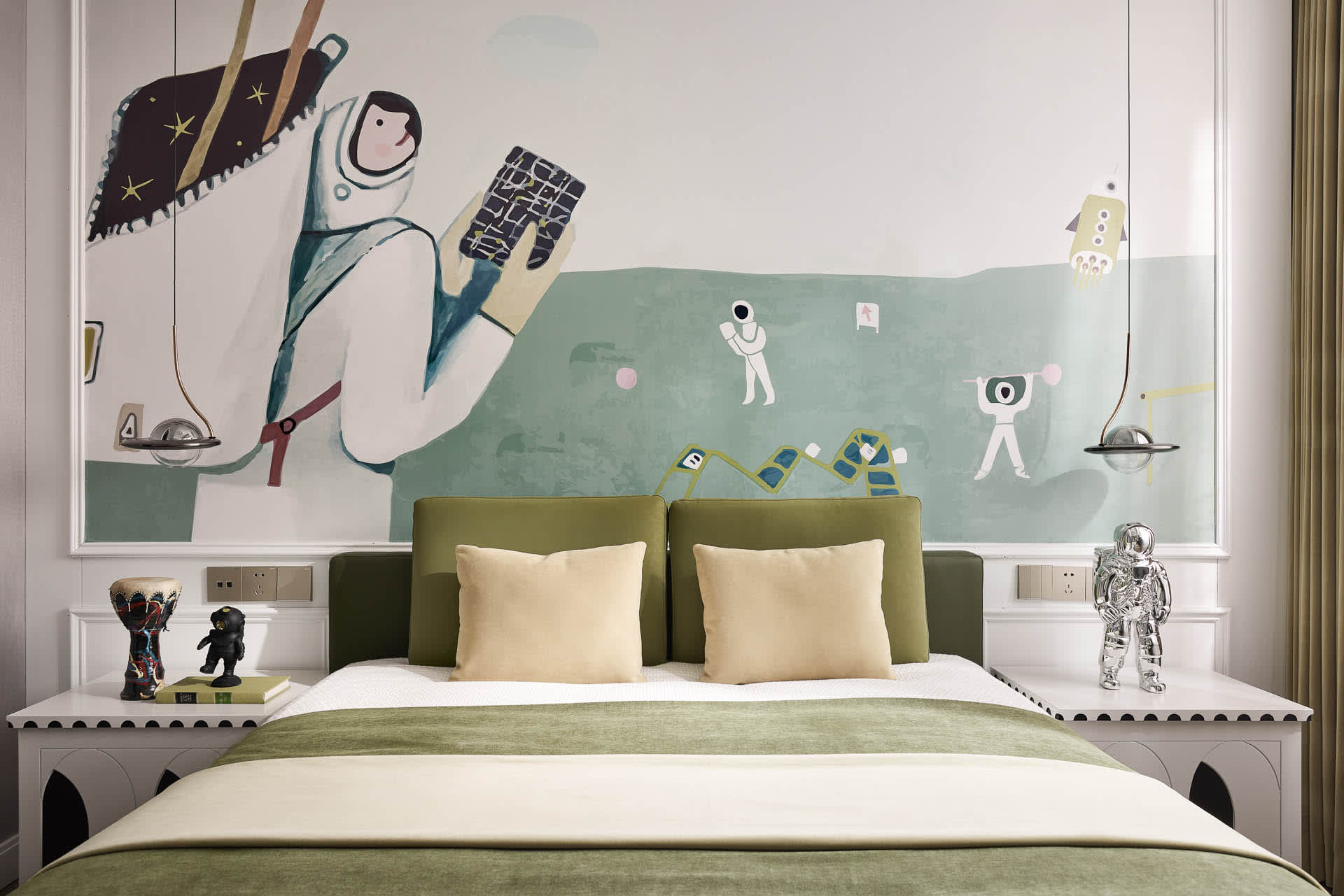 A minimalist bedroom featuring a green upholstered headboard and a playful, astronaut-themed mural on the wall.