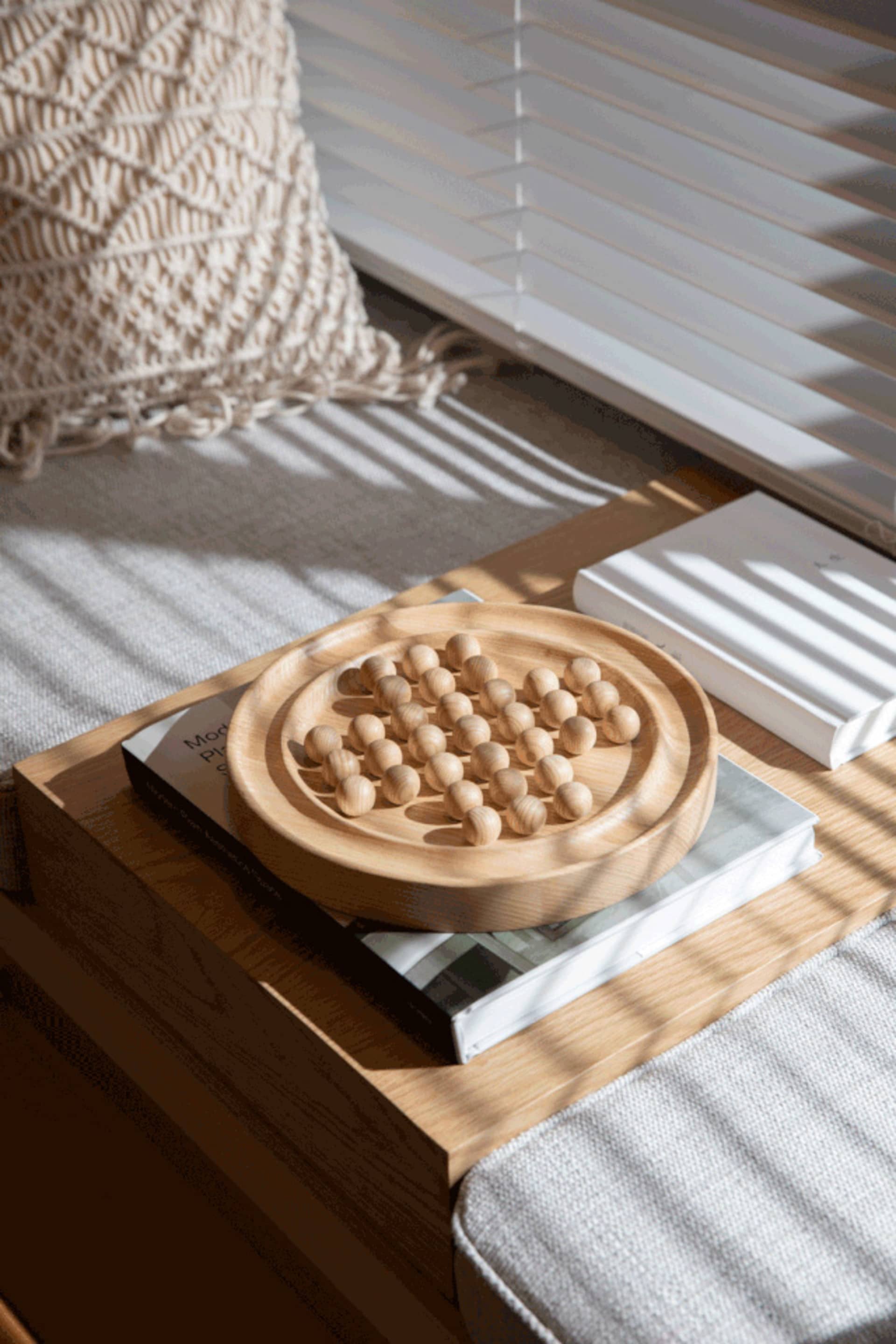 Modern coffee table with a wooden game board containing round wooden beads on a wooden tray.