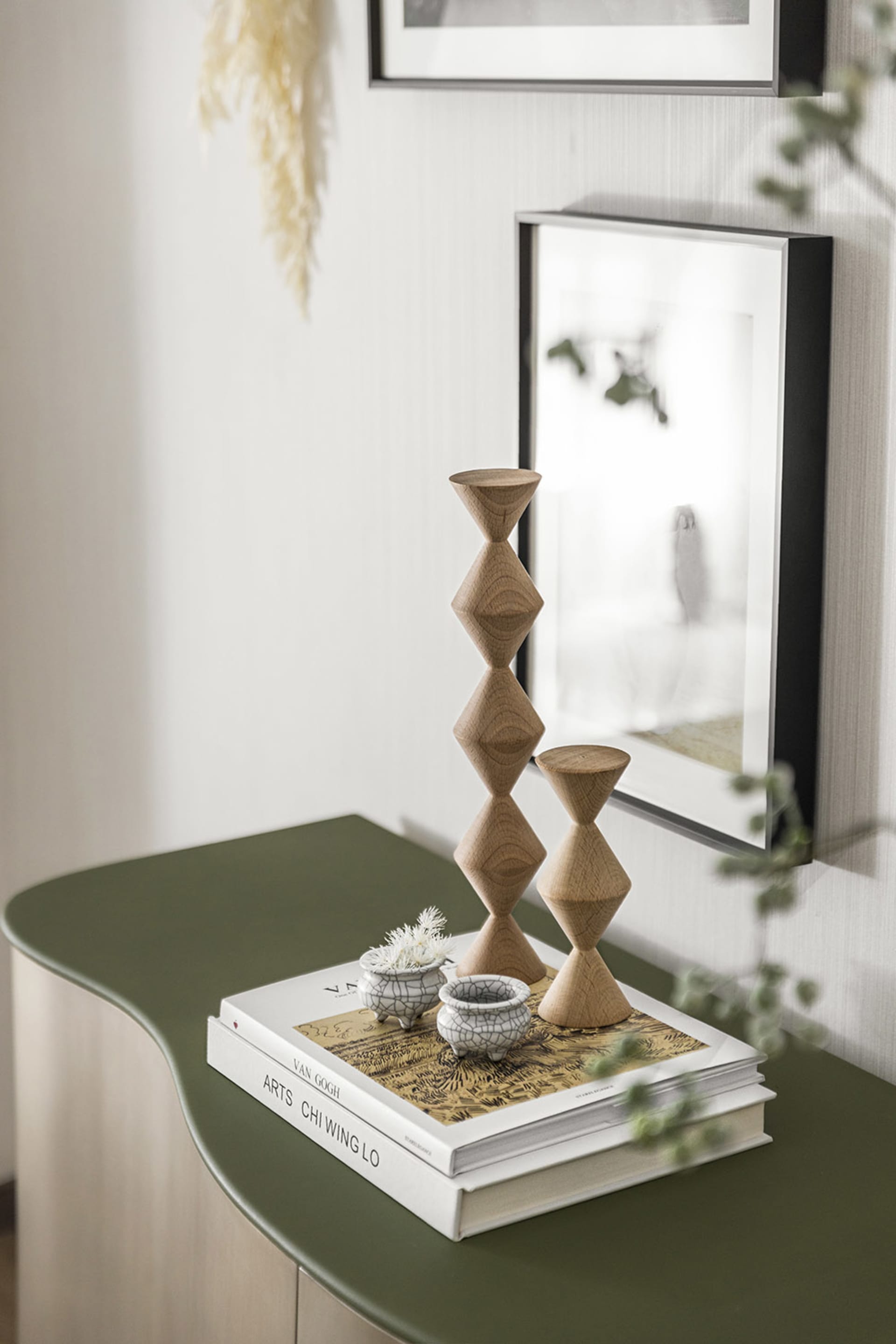 Modern interior design featuring minimalist wooden candlesticks on a green table.