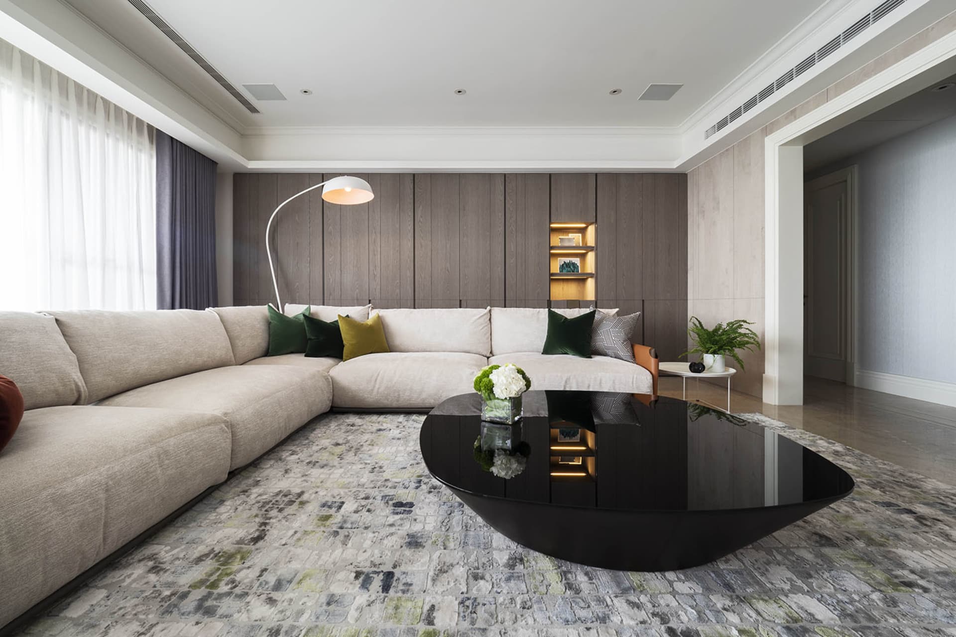 Modern interior design living room featuring a large beige sectional sofa with green and yellow throw pillows, a black coffee