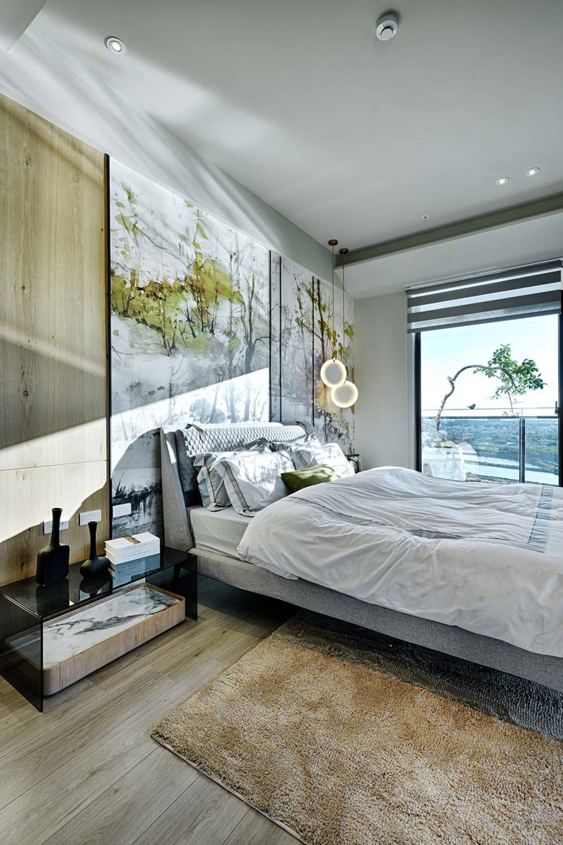 Modern minimalist bedroom showcasing hardwood flooring, a bed with a gray headboard and white bedding, and a large abstract p