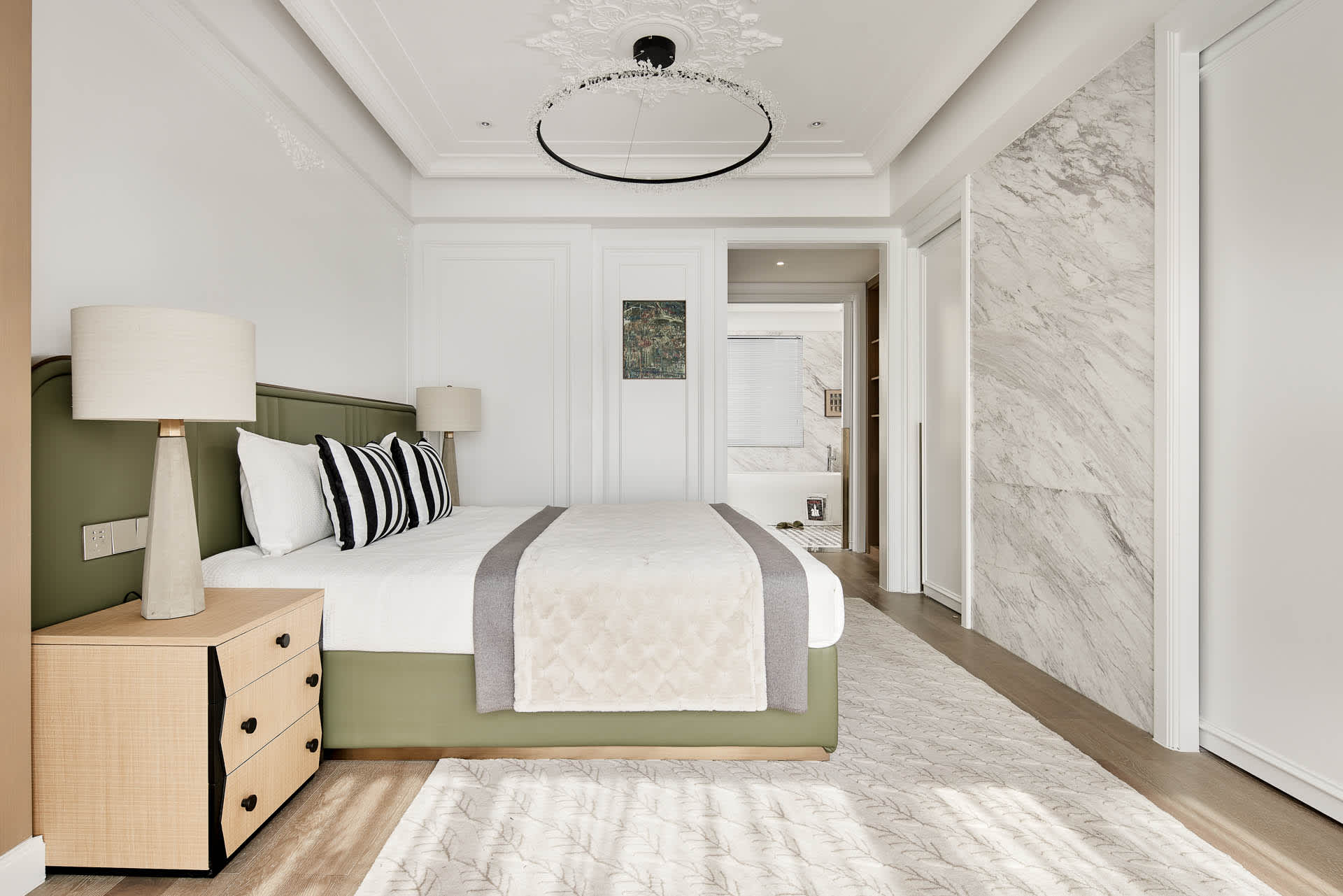 A modern bathroom featuring marble flooring, wooden cabinets, and a green upholstered bed.