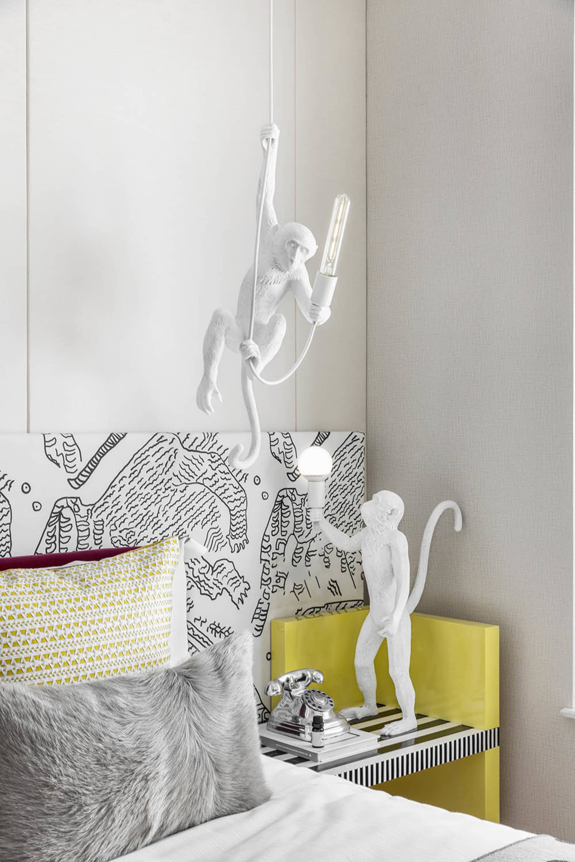 A modern bedroom featuring a unique light sculpture in the shape of a monkey holding a light bulb.