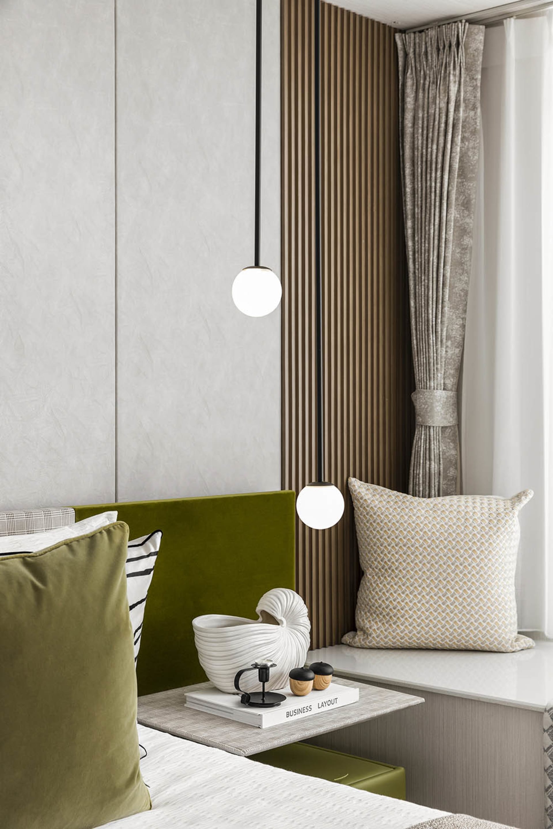 Modern bedroom with green velvet headboard, wooden paneling, and decorative pillows.