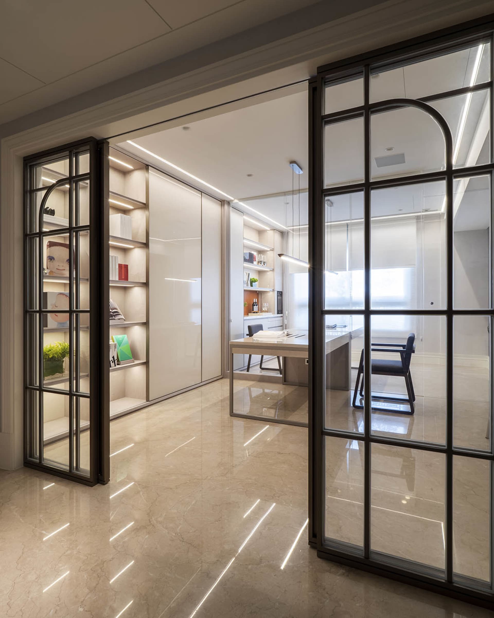 A modern living room featuring glass walls, steel trims, and marble flooring.