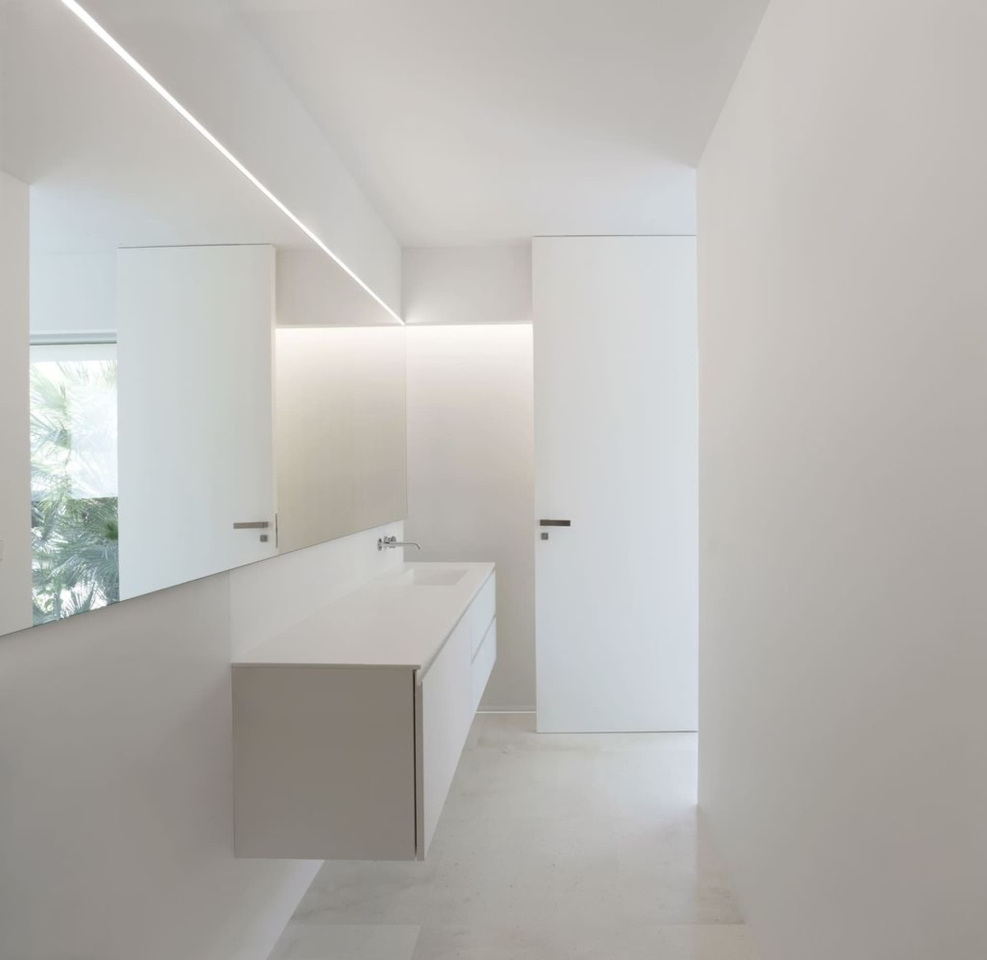 Minimalist bathroom with white walls, featuring a floating vanity and a frosted glass door.