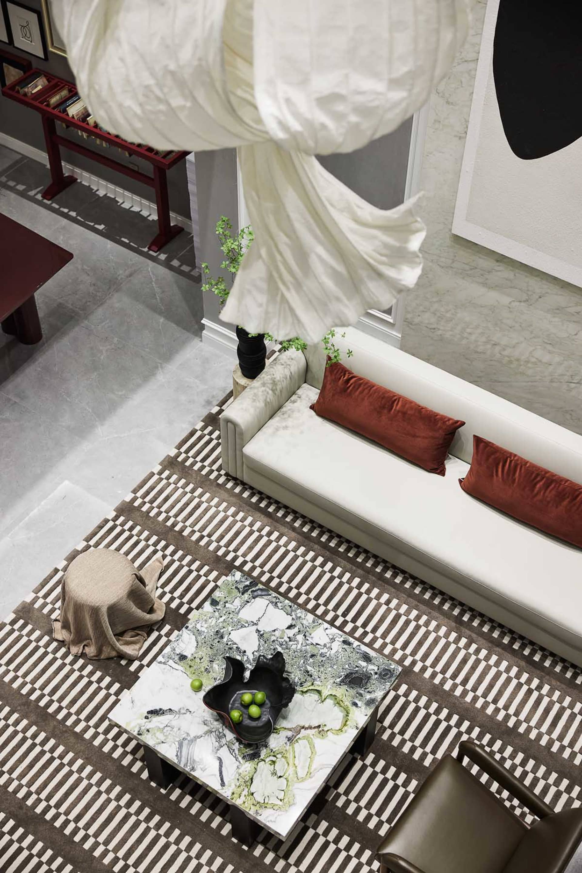A modern living room with white marble coffee table, white sofa with red cushions, and a patterned carpet