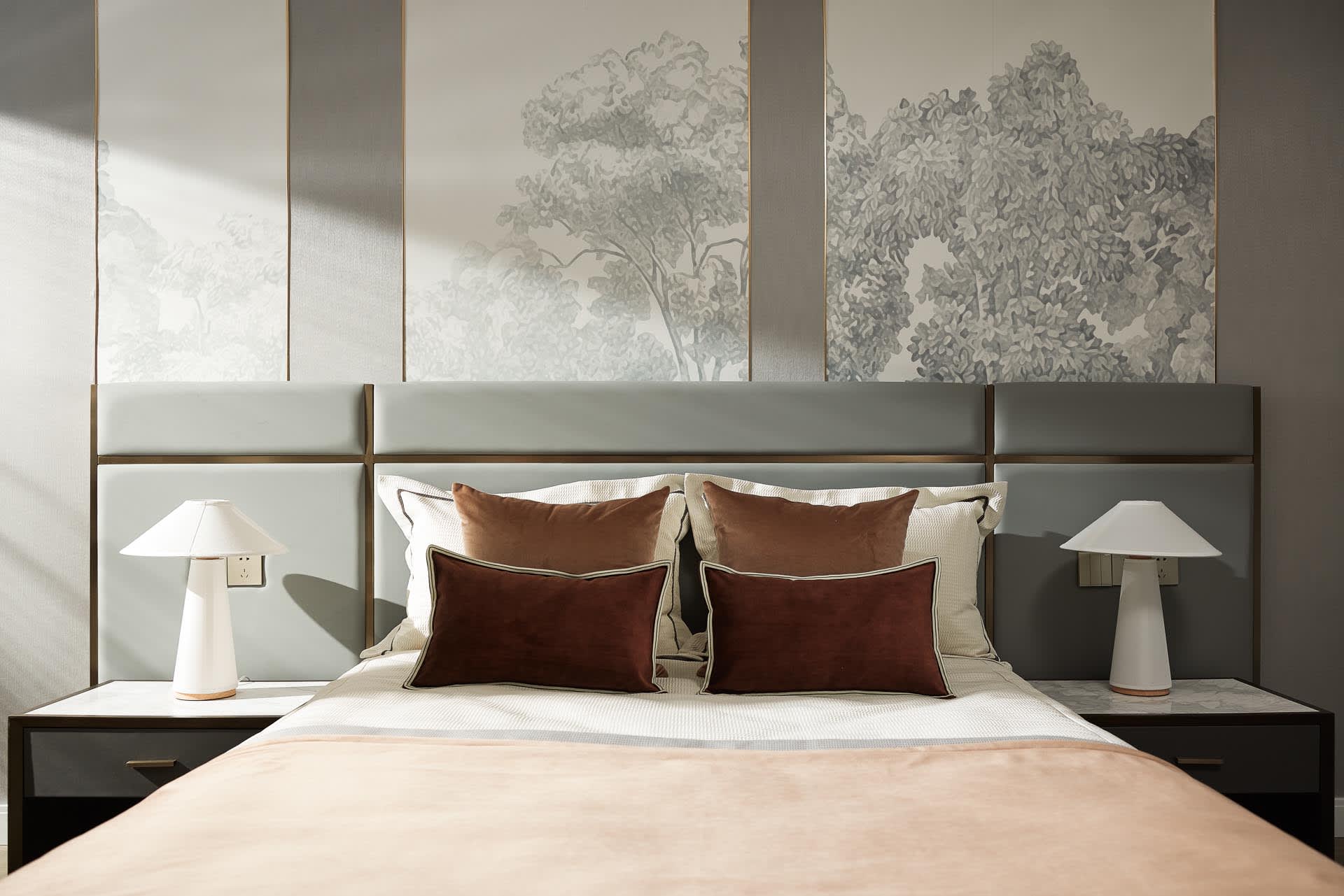 A minimalist bedroom with a bed, two nightstands with lamps, and a headboard with a nature-themed mural.