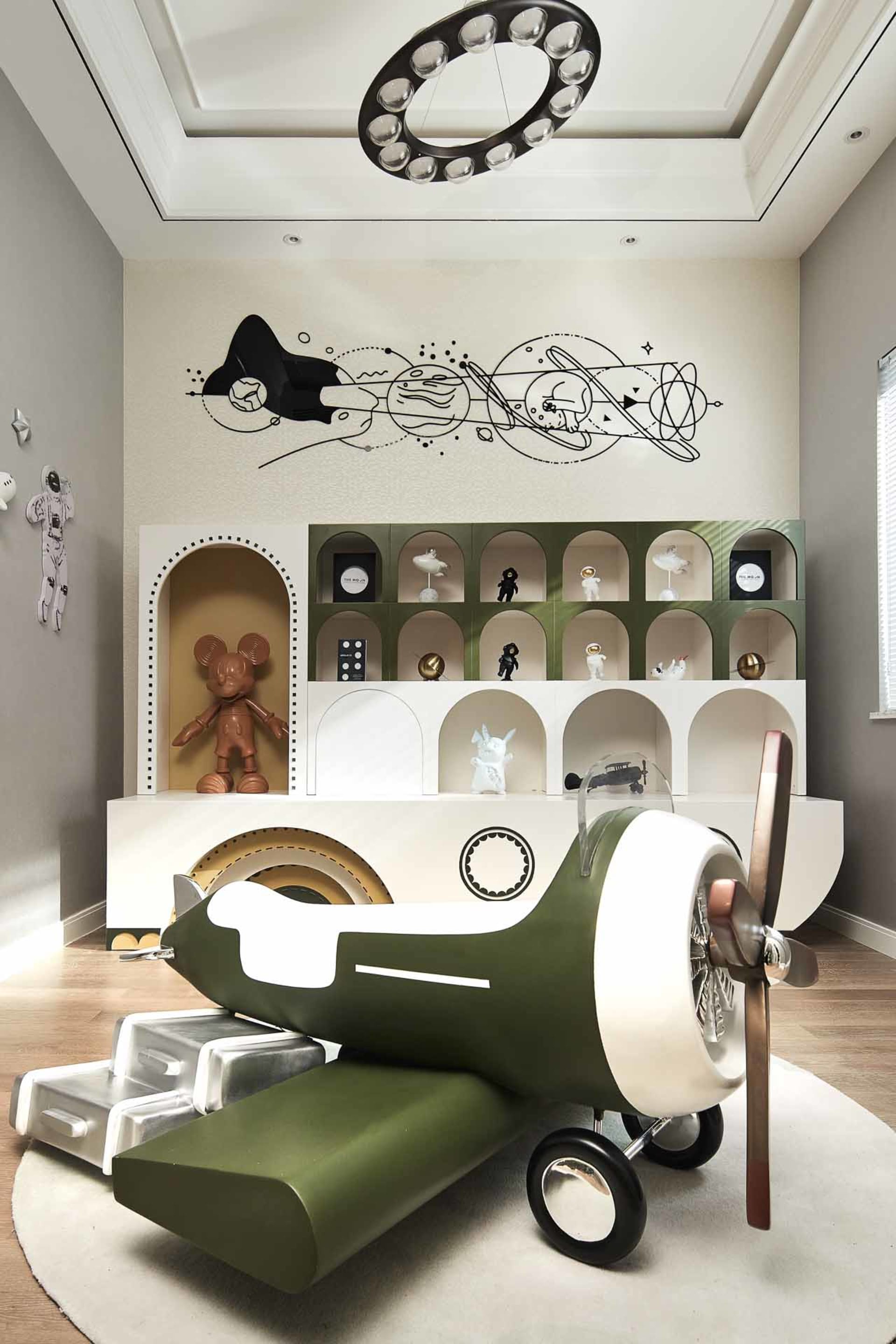 A space-themed child's bedroom with an airplane-shaped bunk bed and a rocketship mural on the wall.