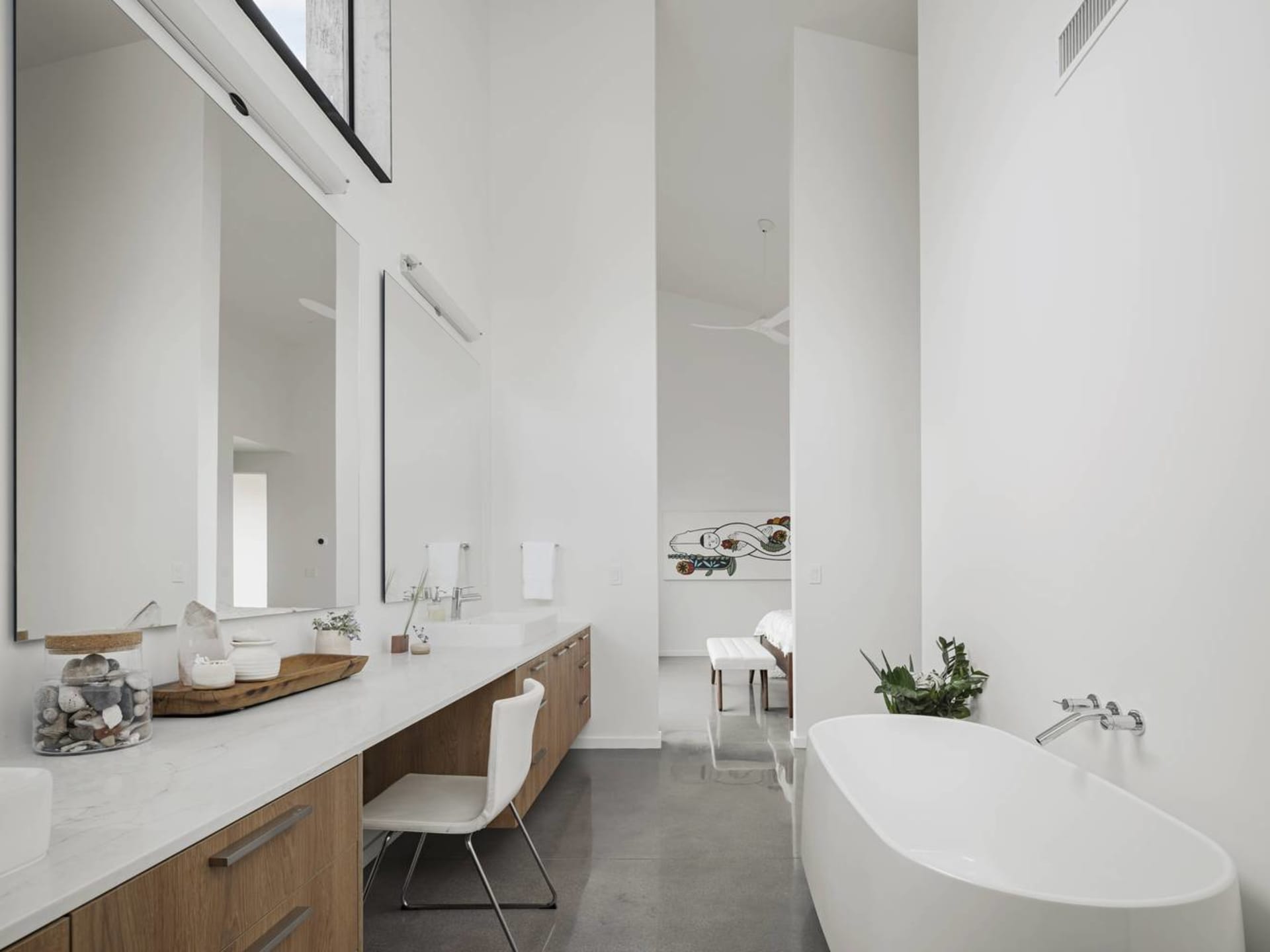 Modern minimalist bathroom with white walls, a white bathtub, and a sleek wooden vanity.