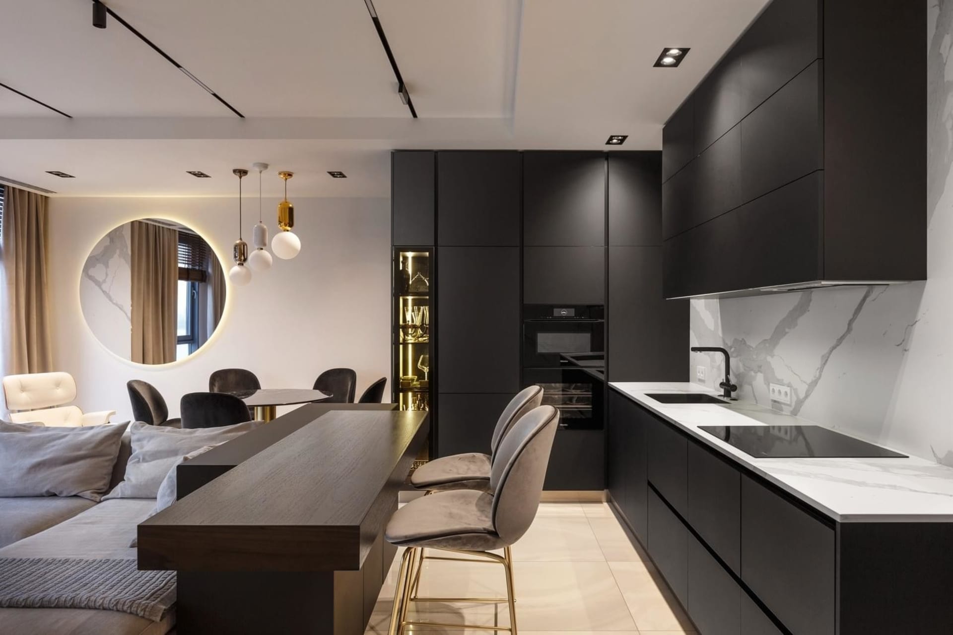 Modern kitchen with black cabinets, marble backsplash, and metal stools.