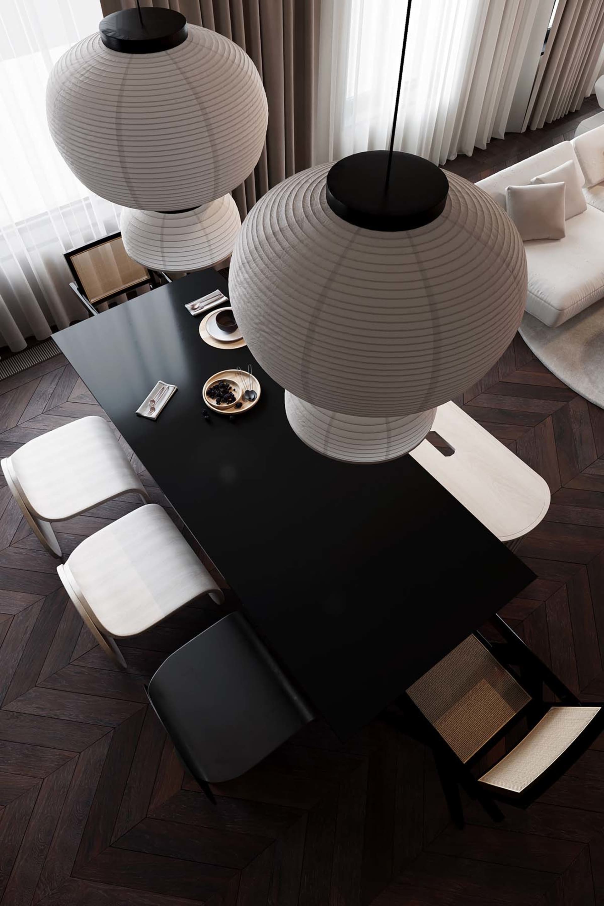 A modern dining room with black glass table, white chairs, and pendant lights.