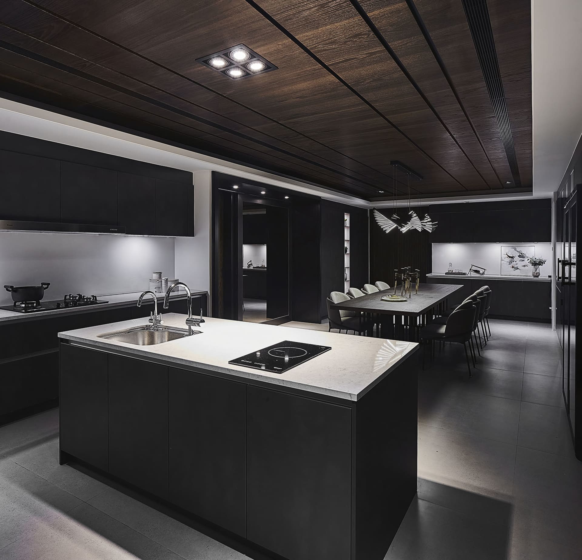 Modern black kitchen and dining room with concrete countertops and dark wood accents