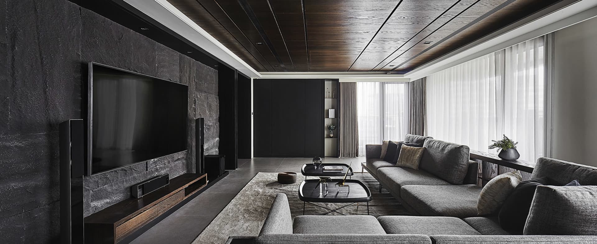Modern living room featuring black walls, glass elements, and concrete flooring.