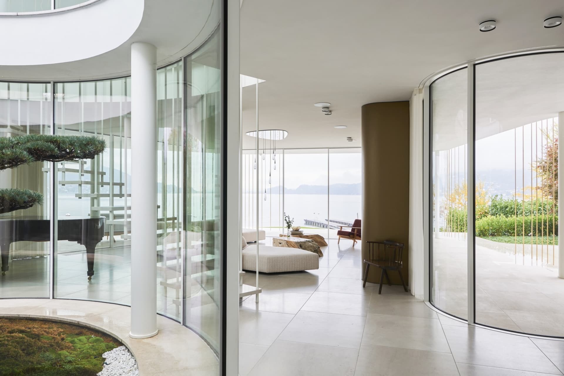 Spacious modern living room with large glass walls overlooking a serene lake