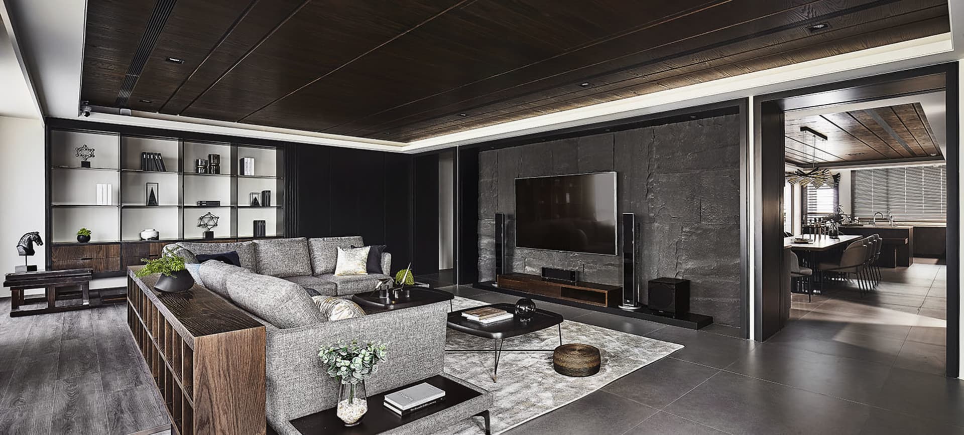 Modern living room featuring a sectional sofa, stone accent wall, and wooden furniture.