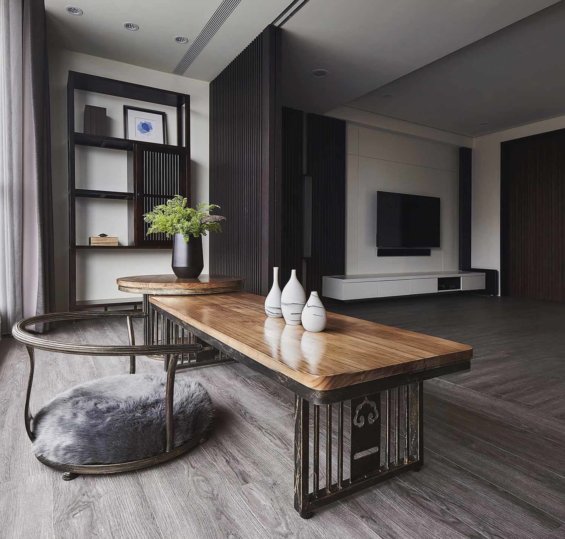 A modern living room featuring wooden furniture and metal tables with decorative vases.
