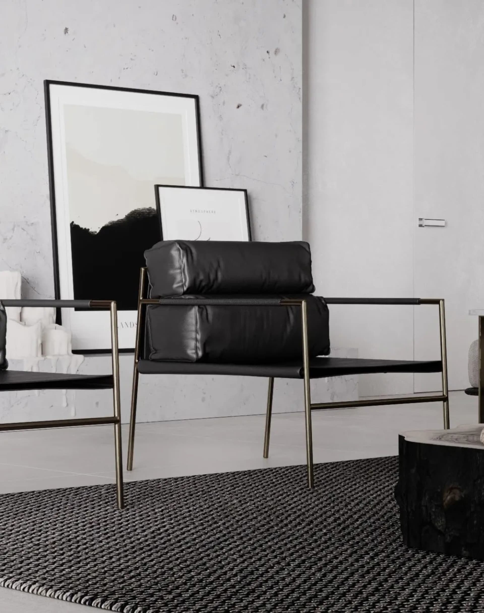 A modern minimalist living room with black leather and gold metal furniture, concrete flooring, and framed pictures on a text