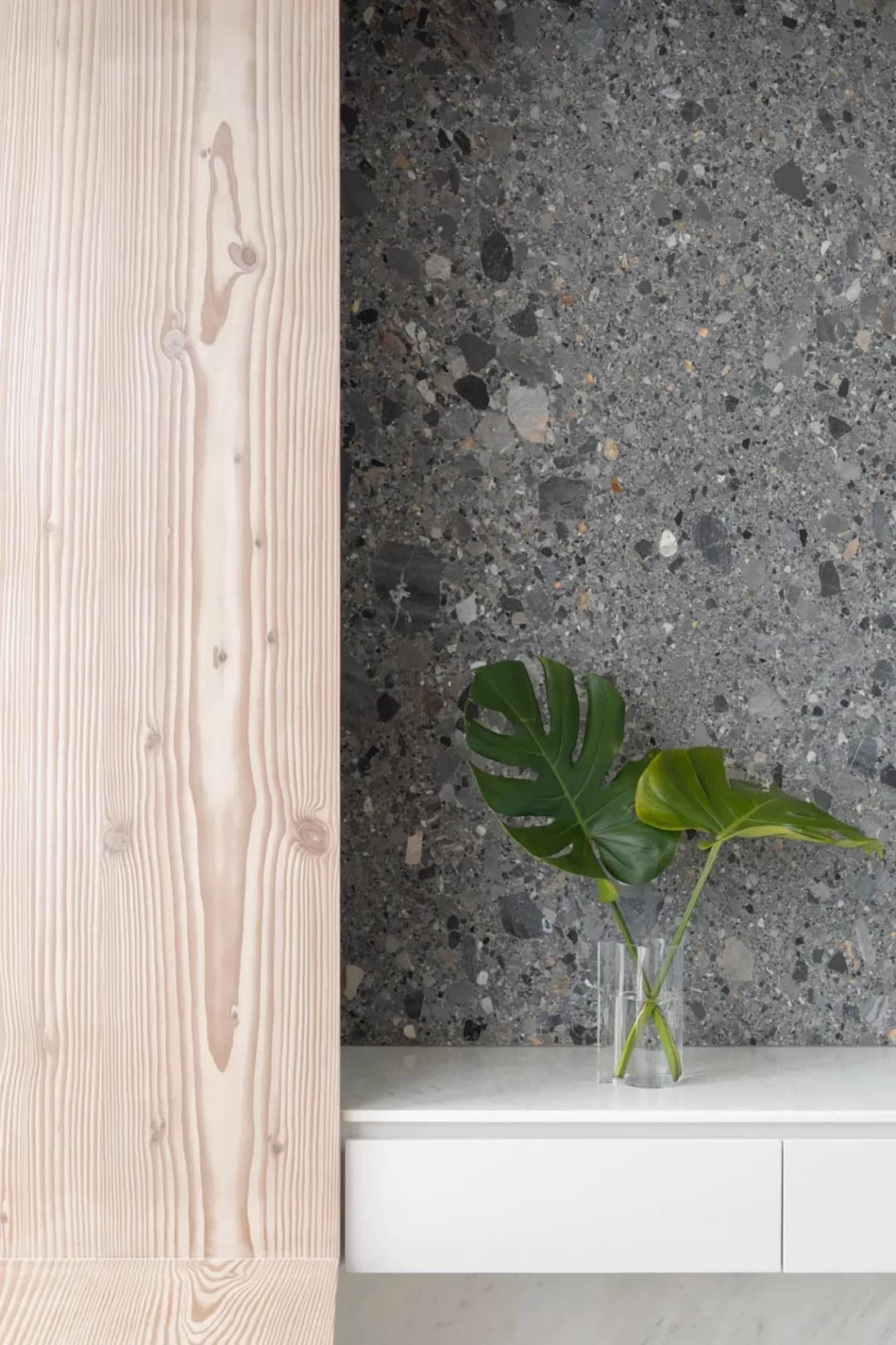 A close-up shot of a modern room featuring white marble, terrazzo, and light wood textures.