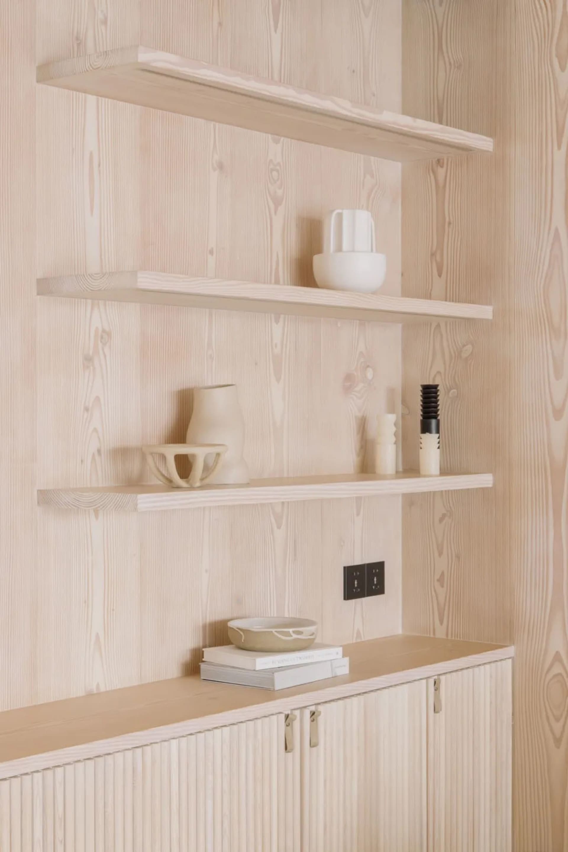 Modern wooden shelf with minimalist decor, including vases and candles.