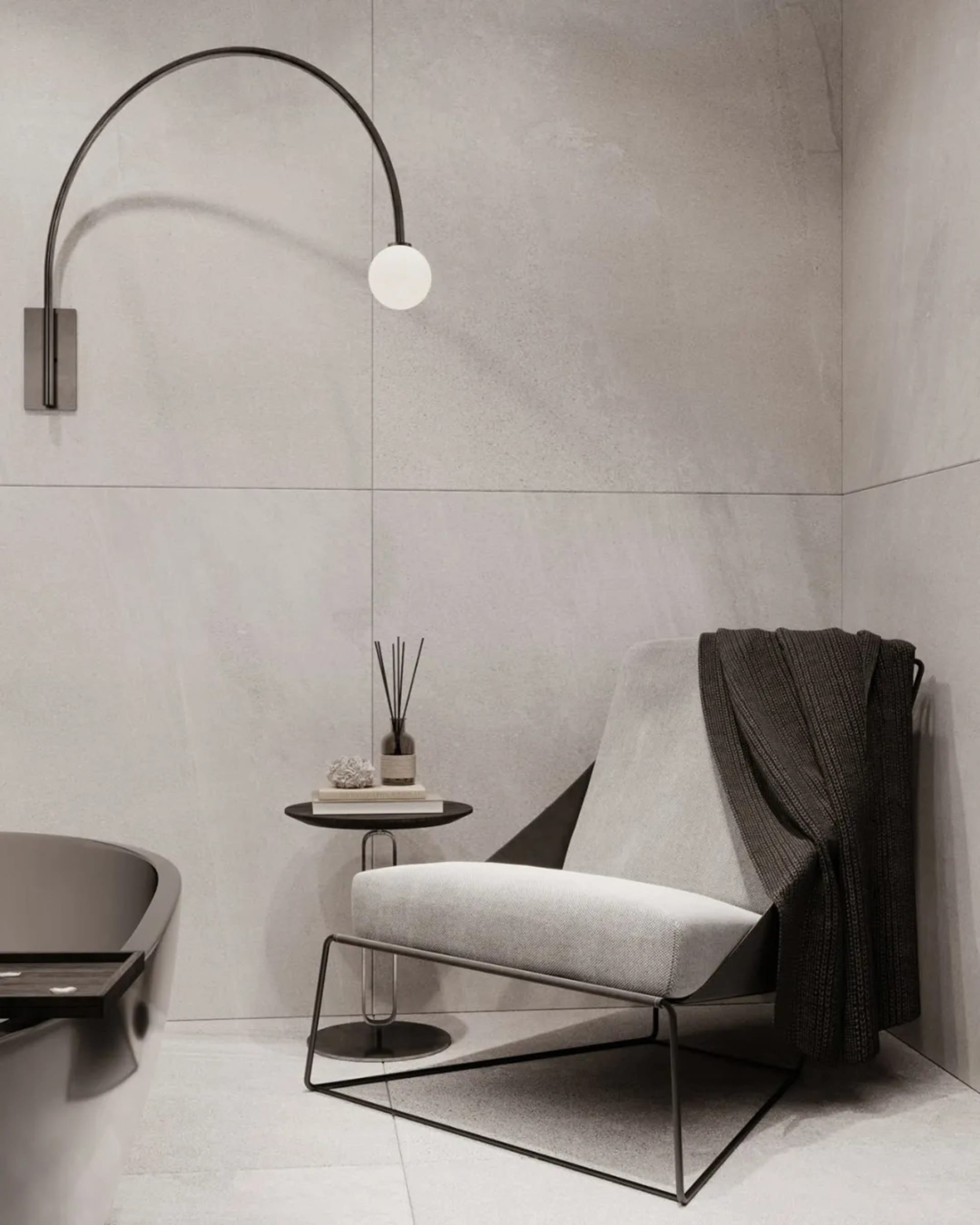 A modern, minimalist home interior featuring concrete walls, a metal-framed chair, and a curved light fixture.