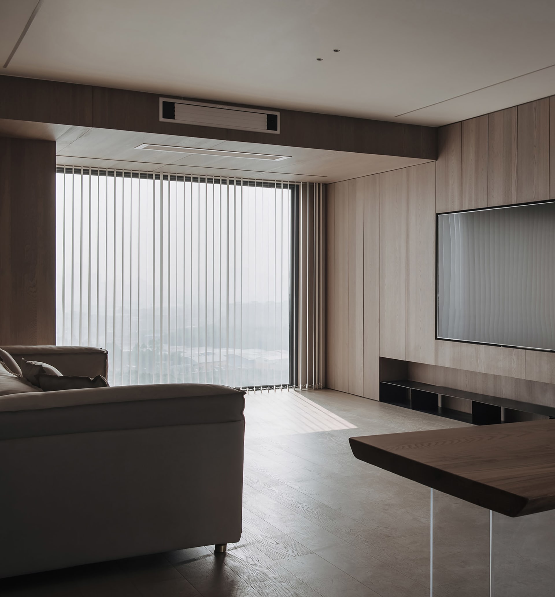 Modern living room featuring minimalist furniture and large windows with vertical blinds.