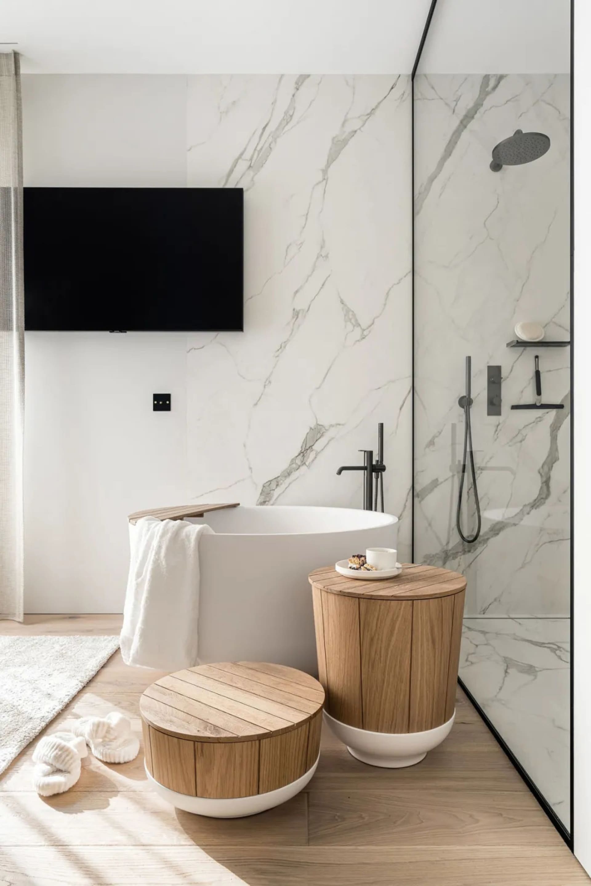 Modern minimalist bathroom with marble walls, porcelain fixtures, and wooden accents.