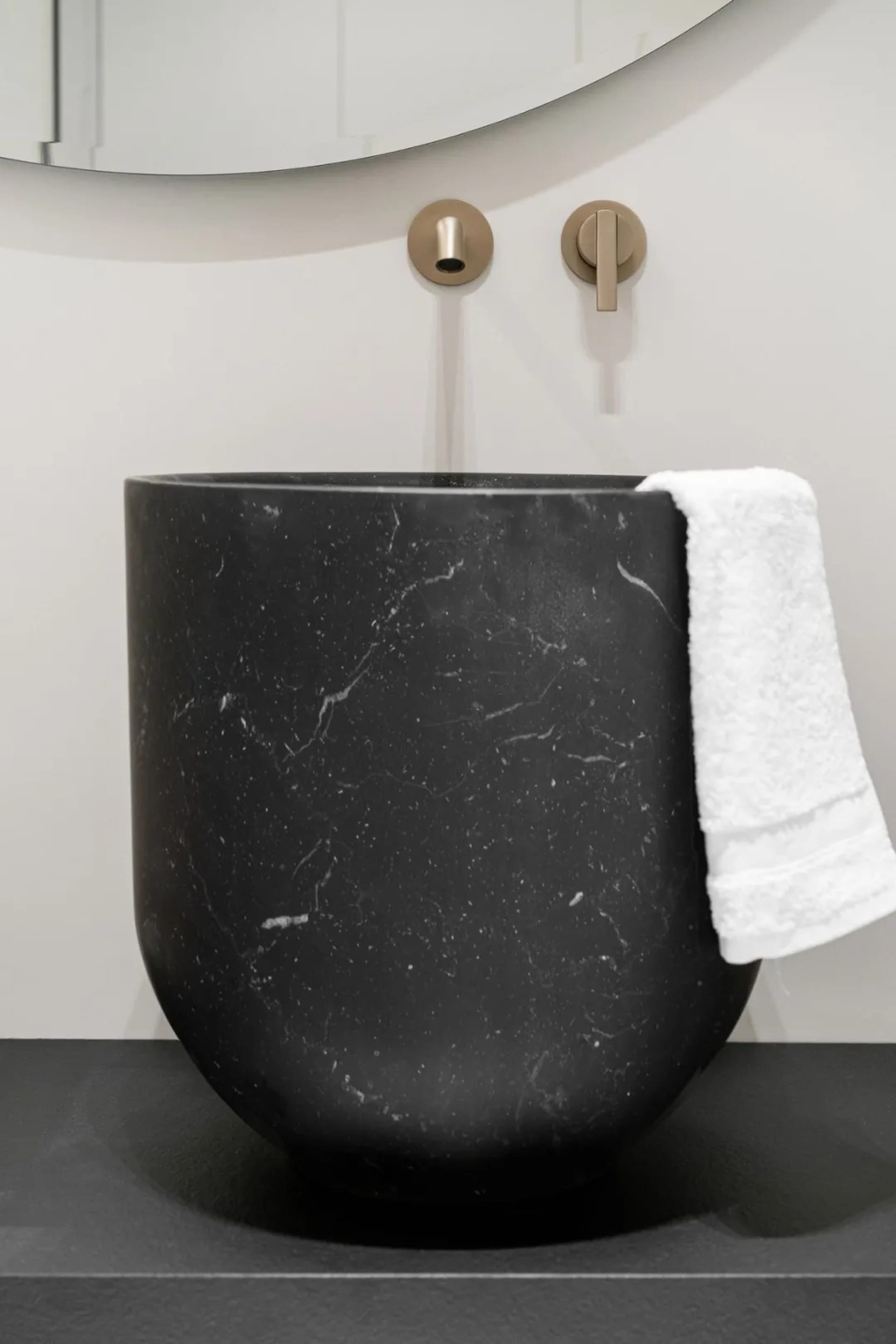 A modern bathroom featuring a black marble sink with a white towel hanging on the side.