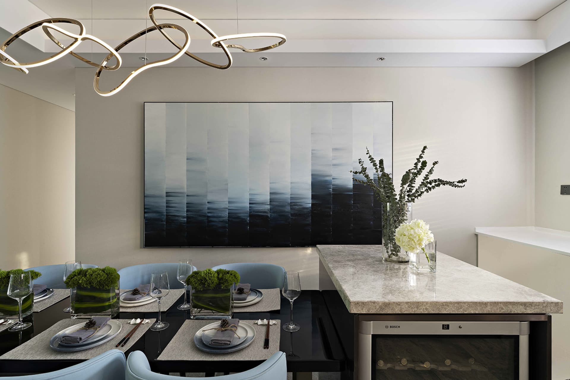 Modern dining room with marble table, glass chandelier, and abstract painting.