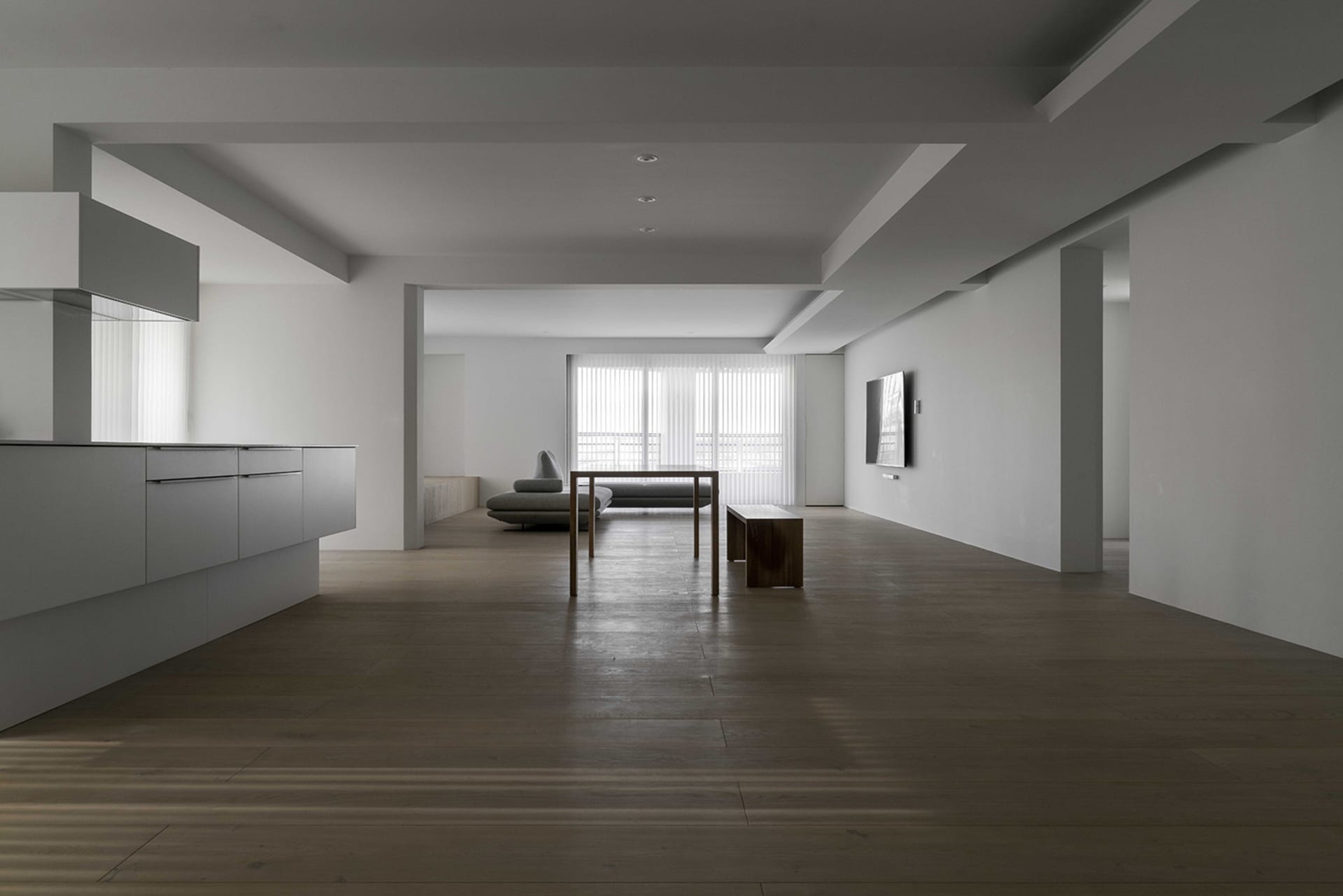 Contemporary minimalist living room with sleek, white furniture and wooden flooring.