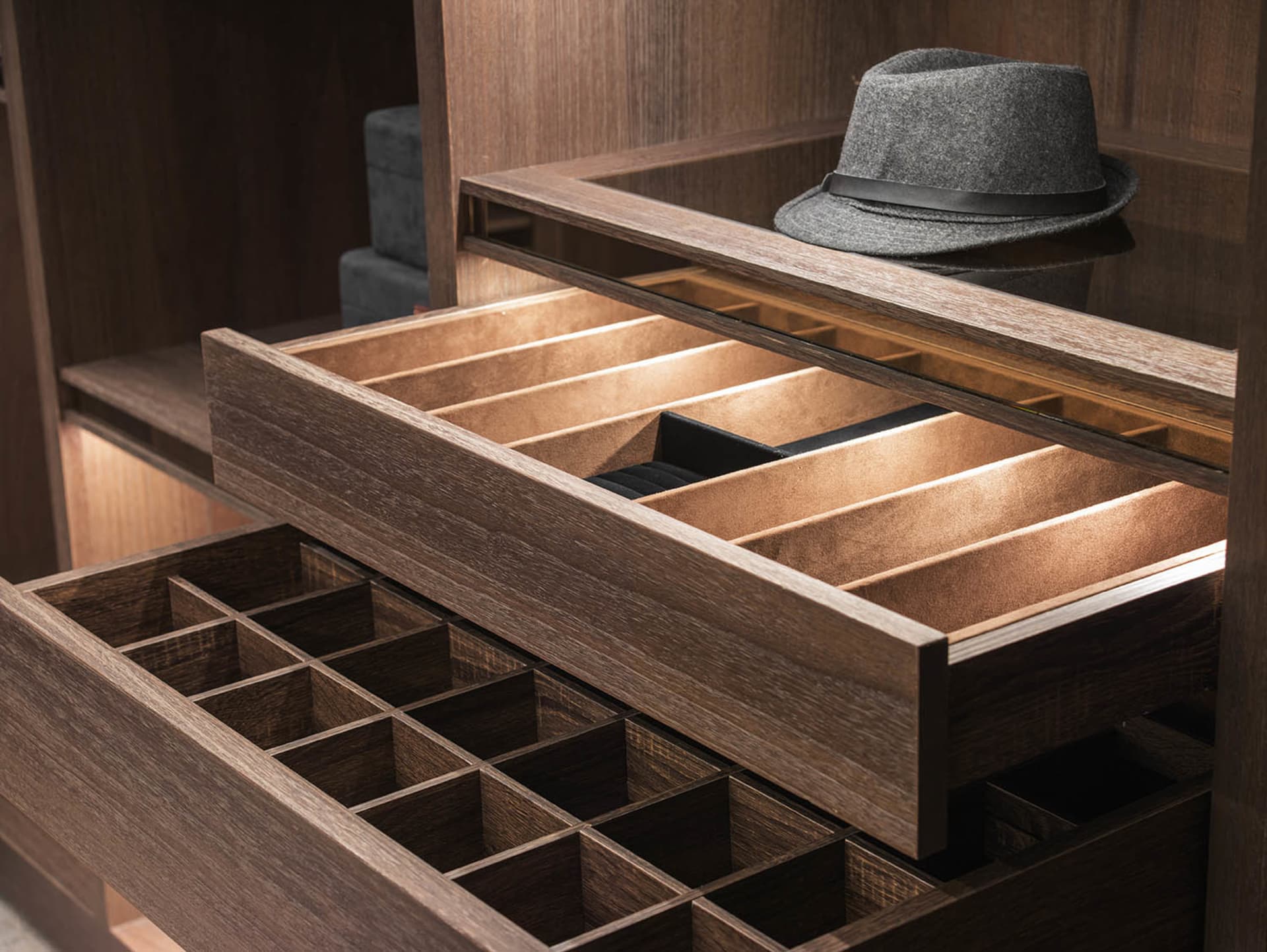 A meticulously organized closet with wooden drawers for hats and other accessories.