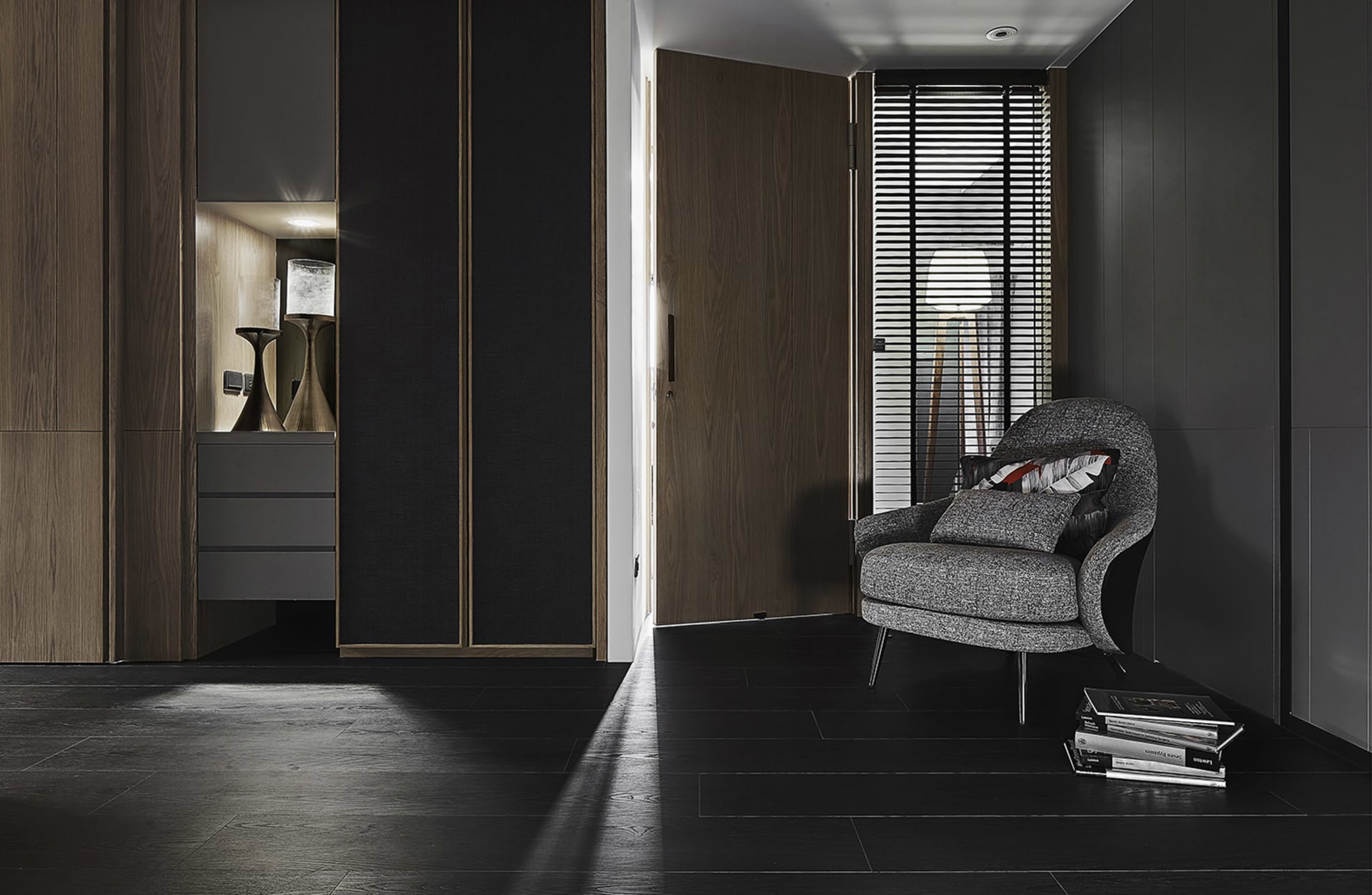 A modern industrial residential entrance with dark wood flooring and a gray upholstered chair.