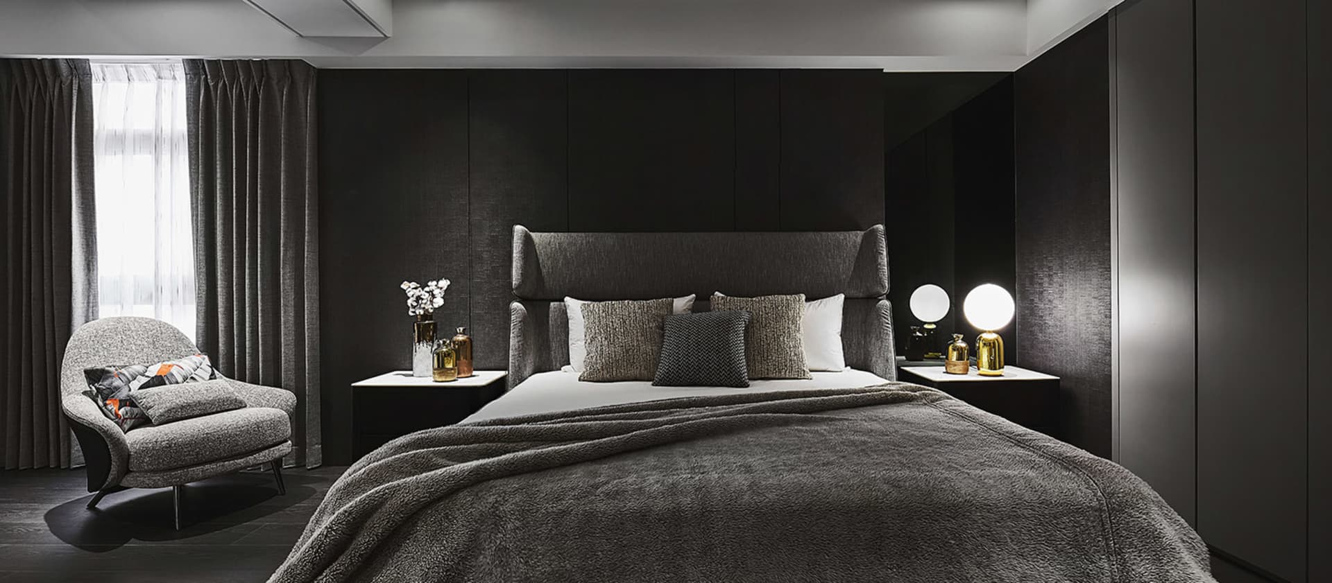 A modern residential bedroom featuring textured fabric upholstery on the bed and armchair.