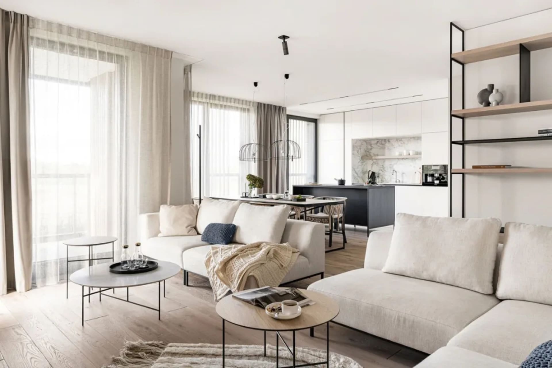 Modern living room with neutral-toned furniture and decor, natural light, and open floor plan.