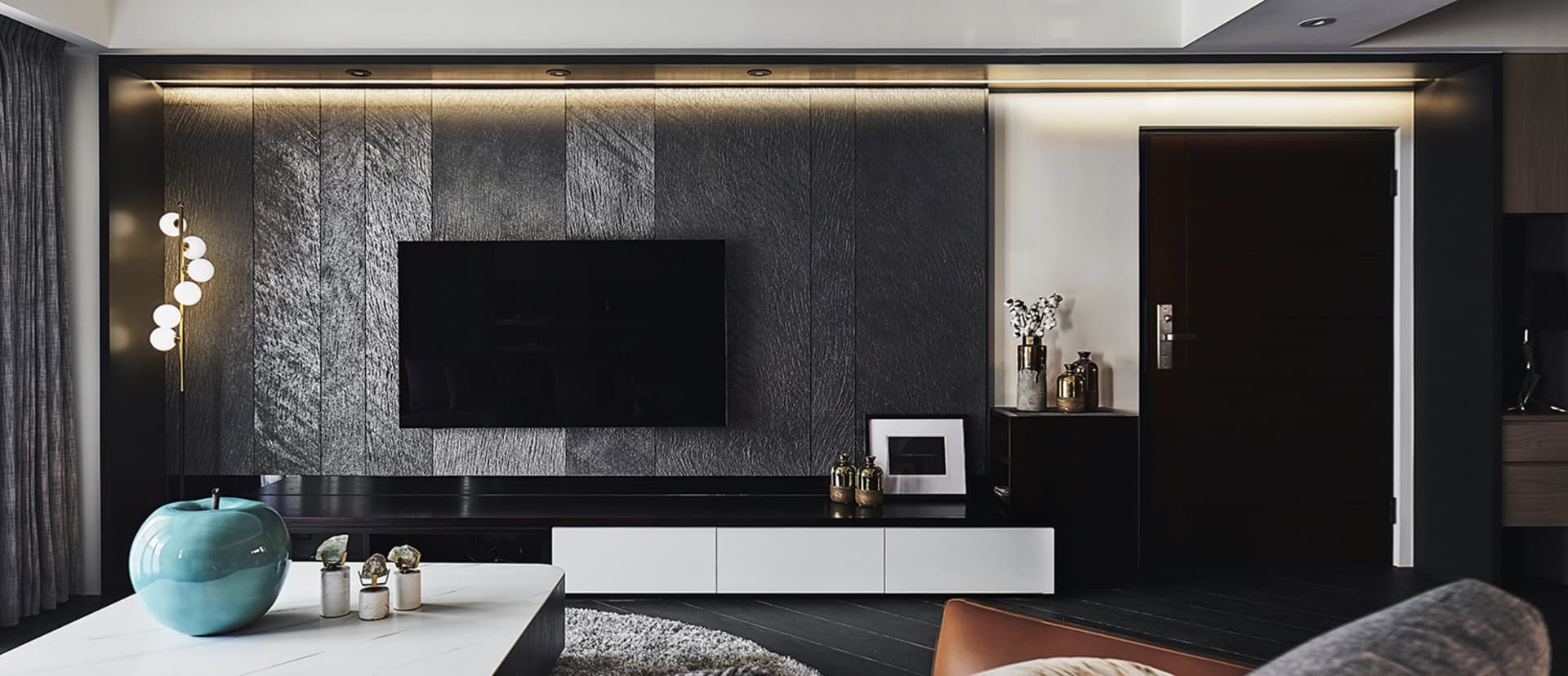 A modern living room featuring metallic texture panels, a flat-screen TV, and minimalist furniture.