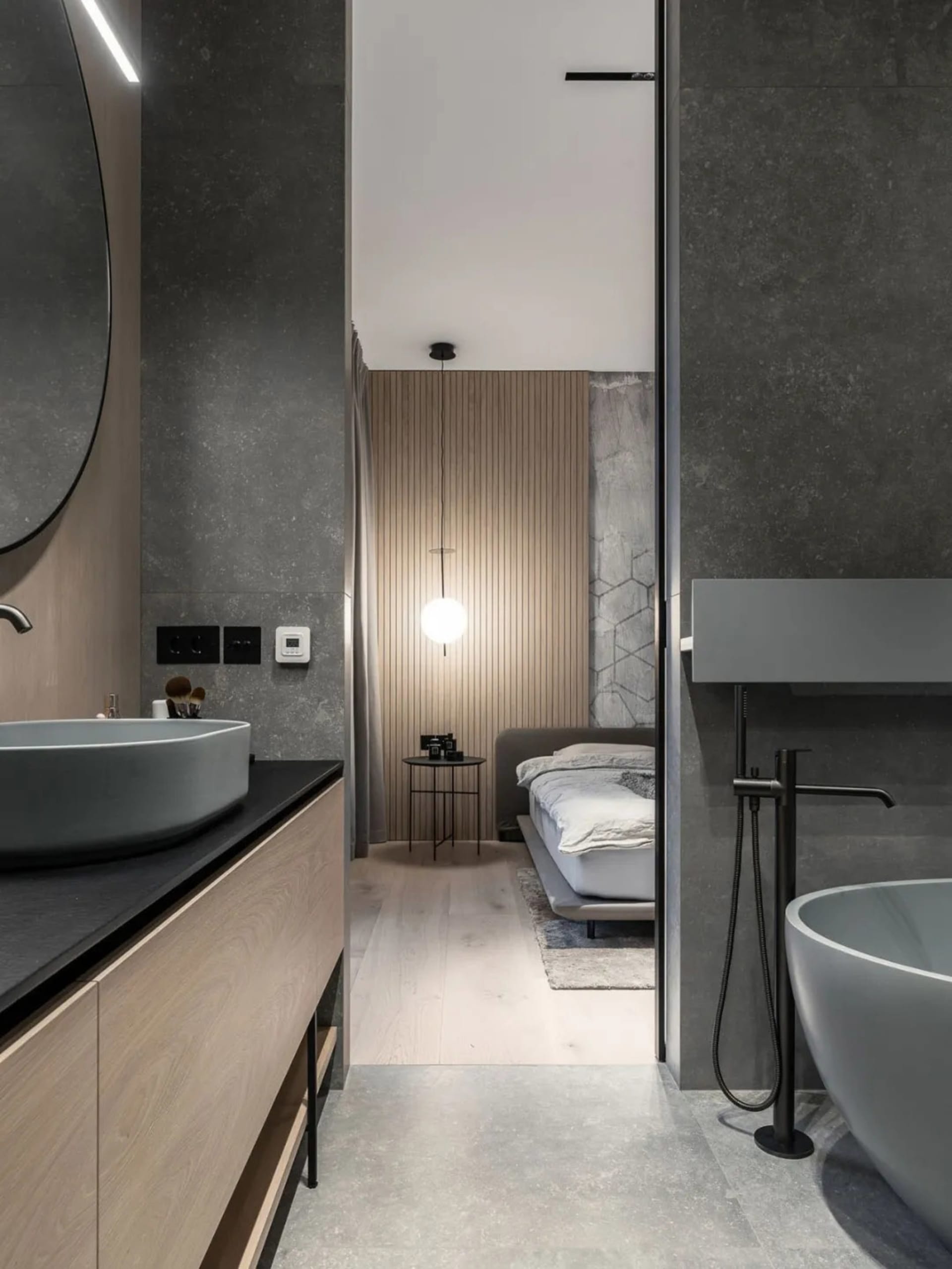 Modern bathroom with concrete walls and wooden finishes, featuring a freestanding bathtub and a floating vanity with a round 