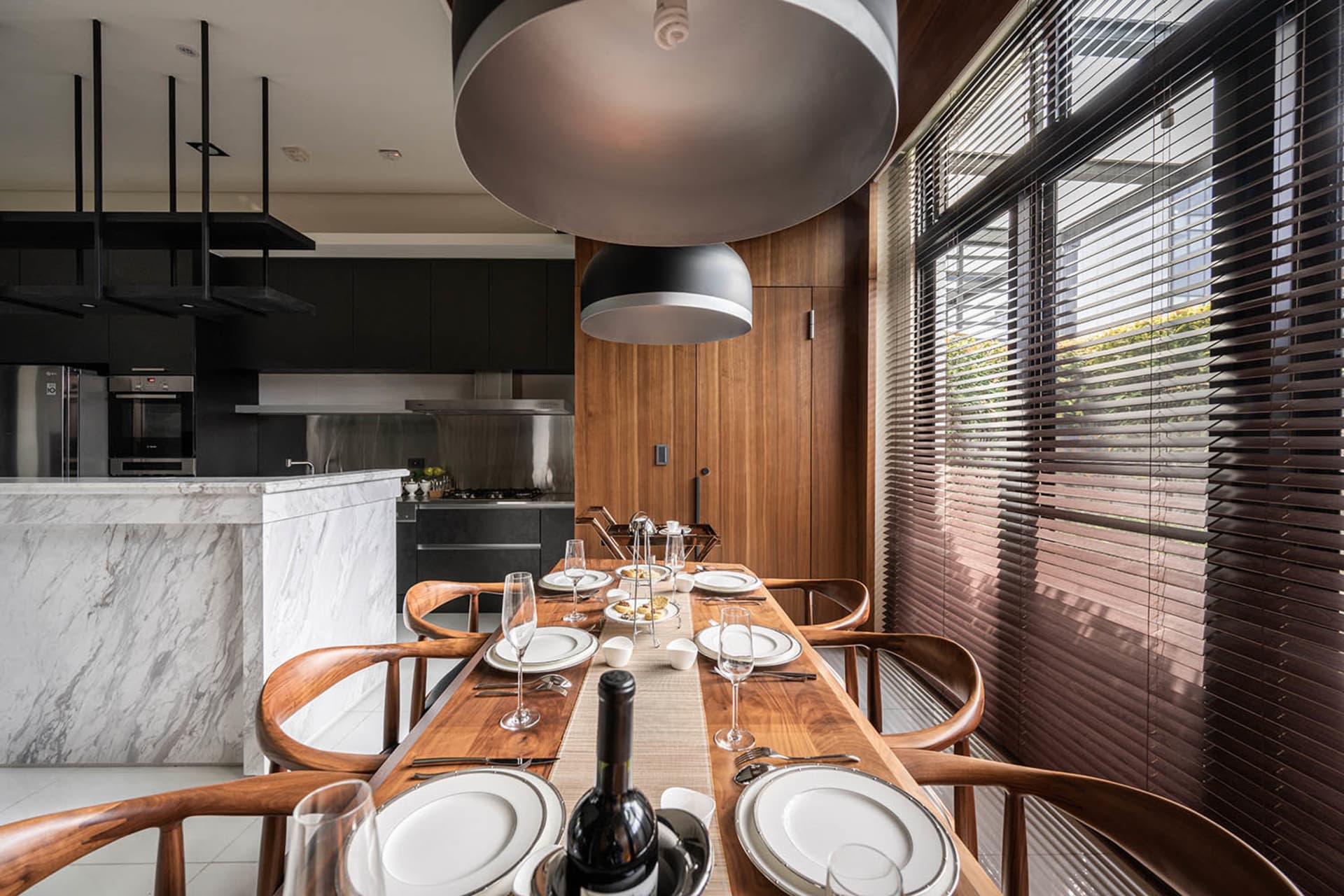 Modern industrial kitchen and dining area featuring wood, marble, and black metal elements.