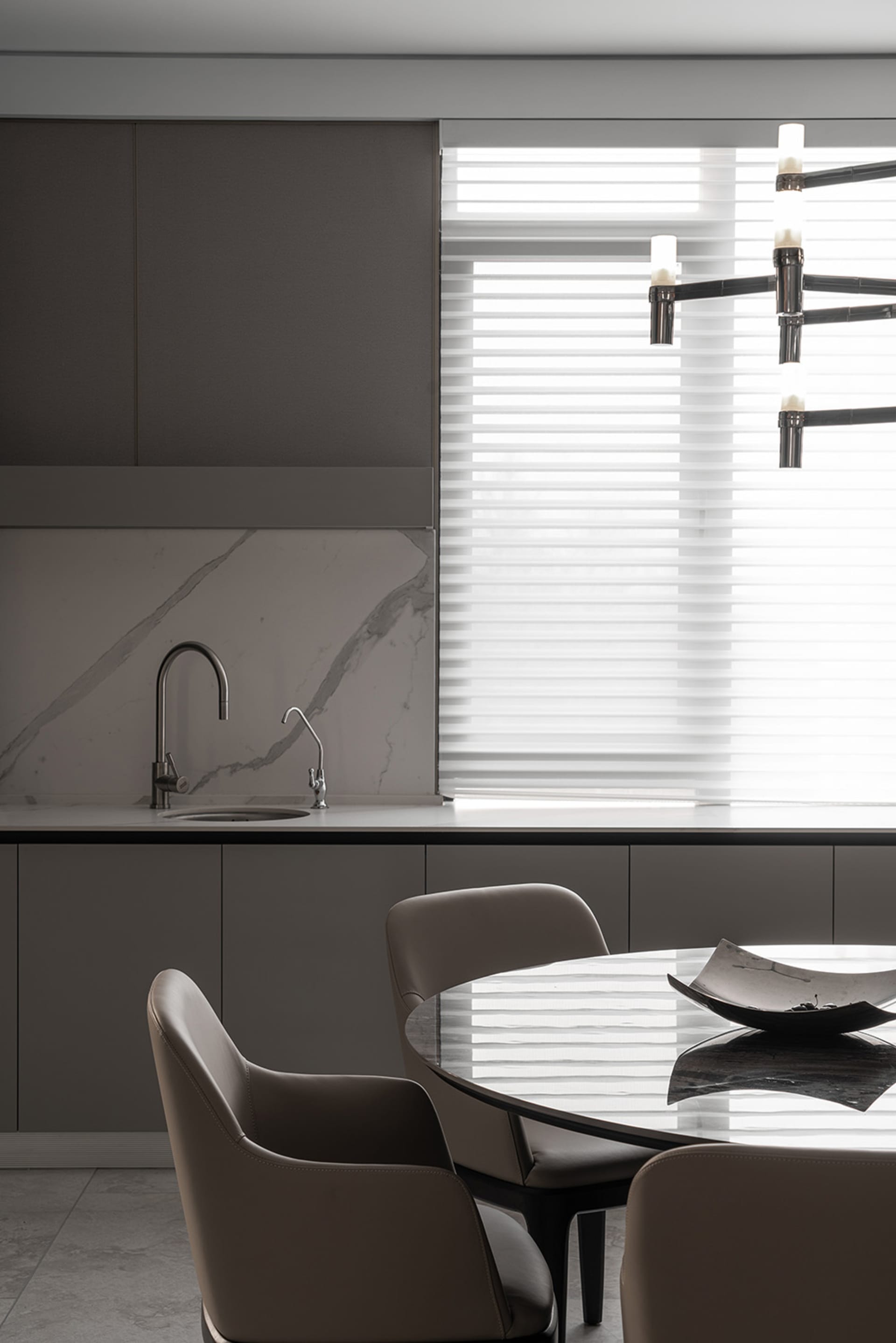 A modern kitchen with marble countertops and a dining area featuring a round table and chairs.