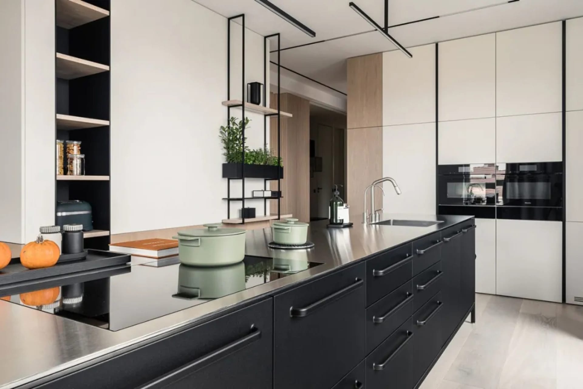 A contemporary kitchen with sleek black cabinetry and metallic finishes, featuring industrial-style lighting and a minimalist