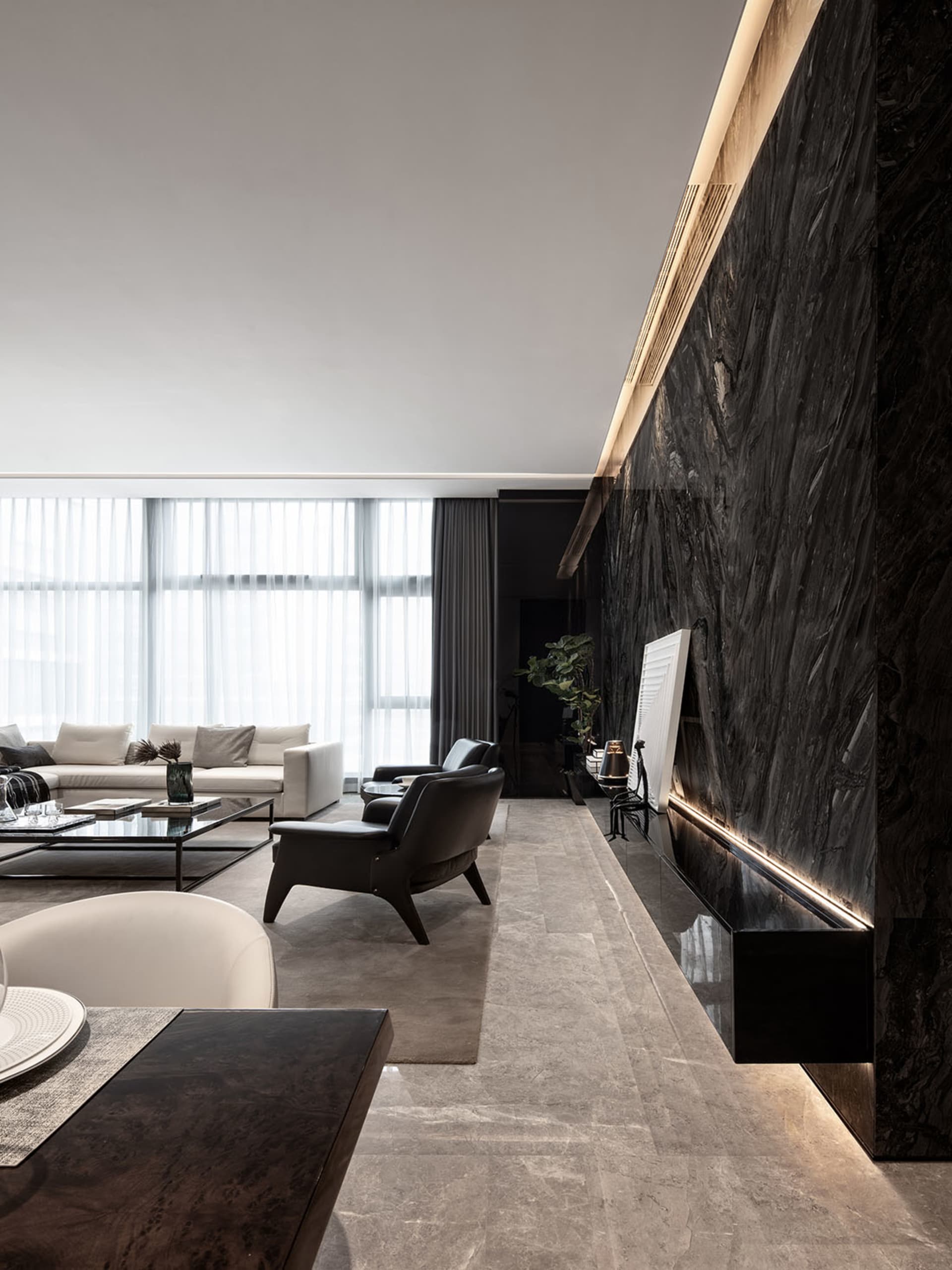 A modern living room featuring marble walls and furniture, with white sofas and black armchairs, large windows, and minimalis