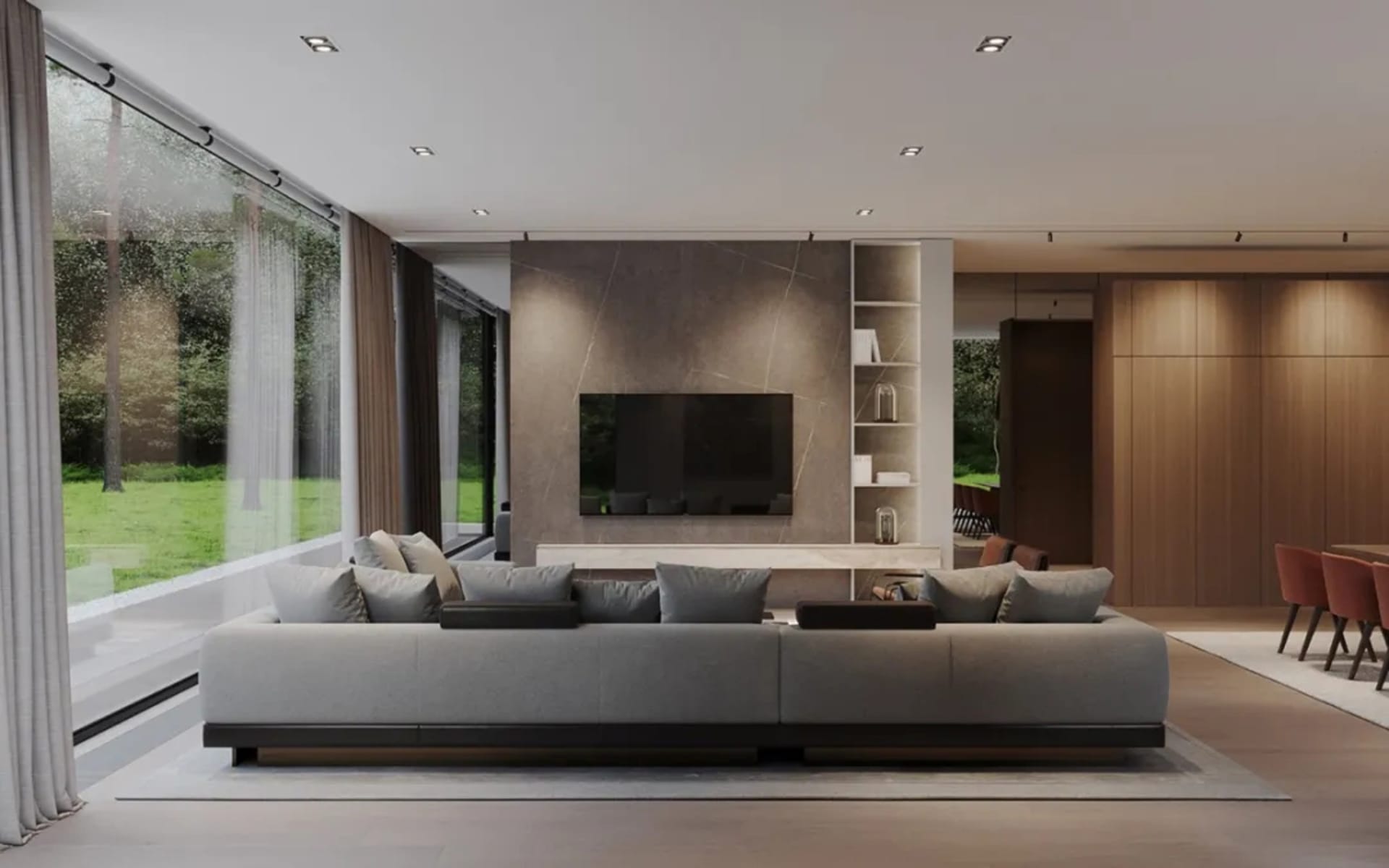 A modern living room featuring a concrete and stone wall with a large sofa and large windows looking out to greenery.